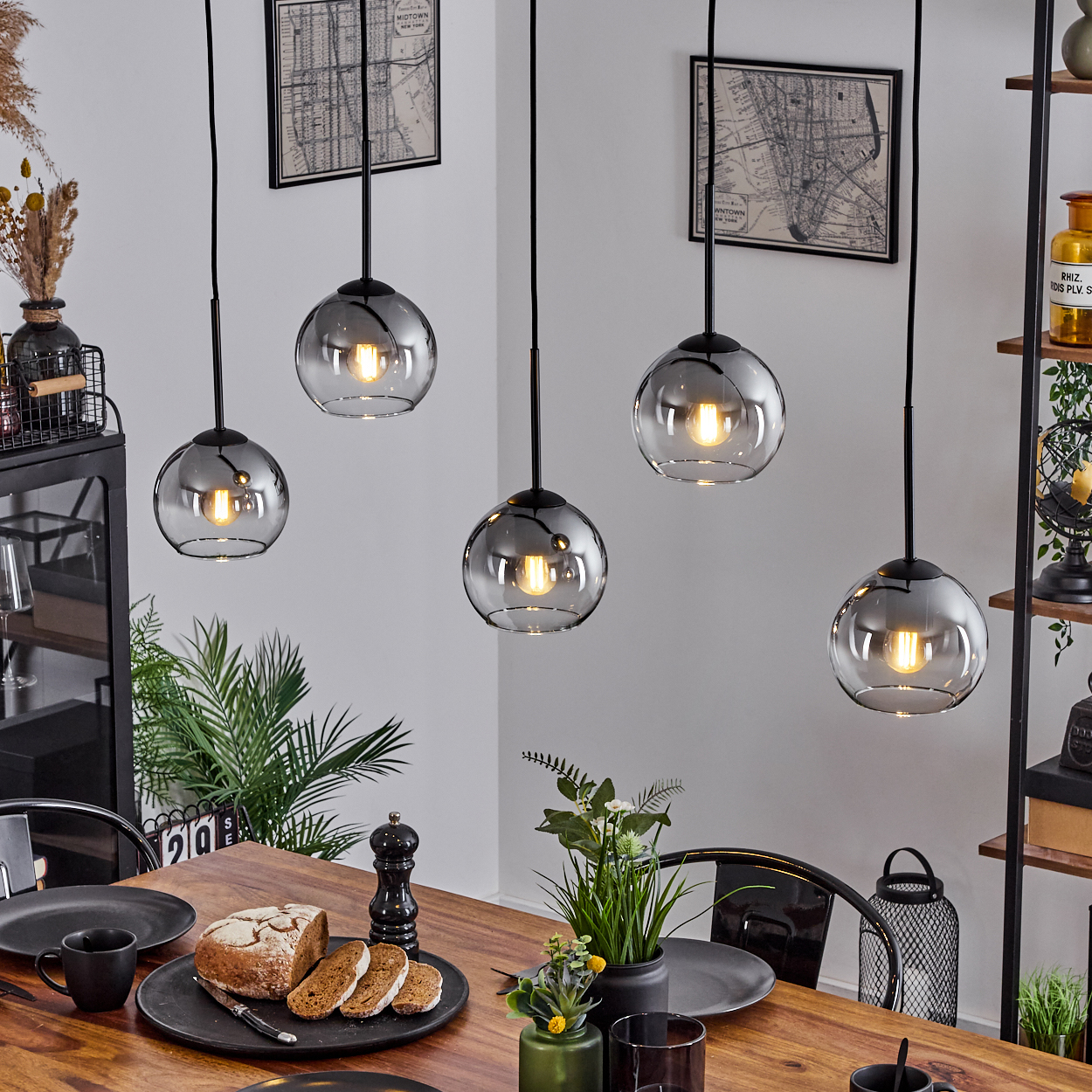 Ein Esszimmer mit Holztisch und fünf silbernen Pendelleuchten.