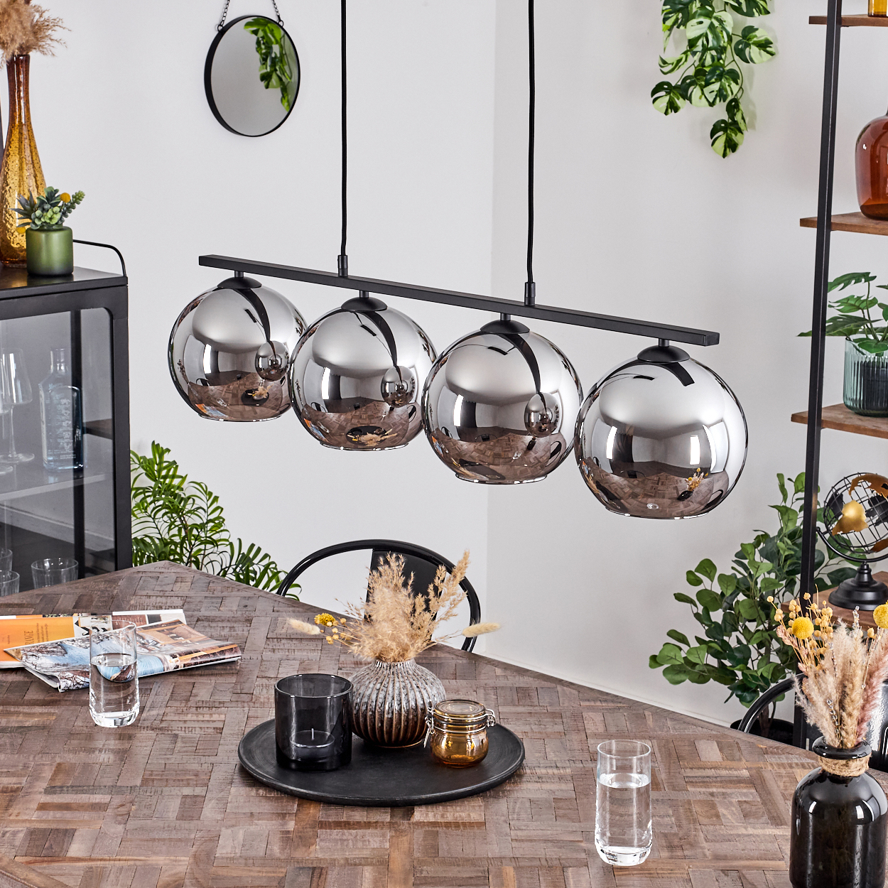 Ein Esszimmer mit Holztisch und vier silbernen Pendelleuchten.