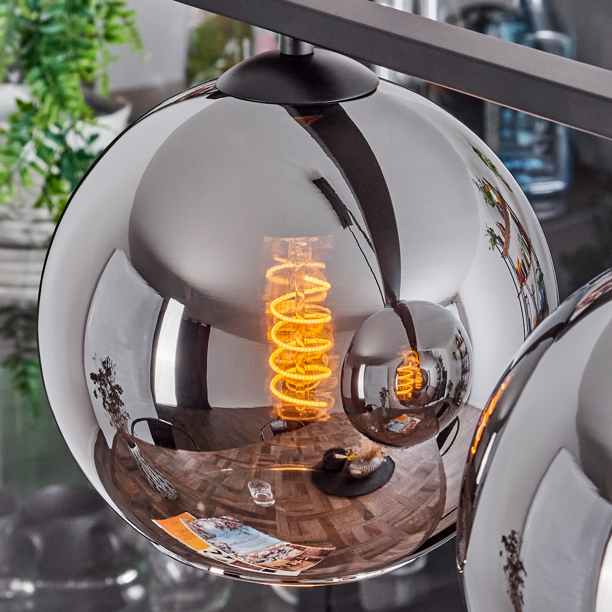 Nahaufnahme einer reflektierenden Kugellampe mit einer Wendelbirne. Der Hintergrund ist verschwommen.