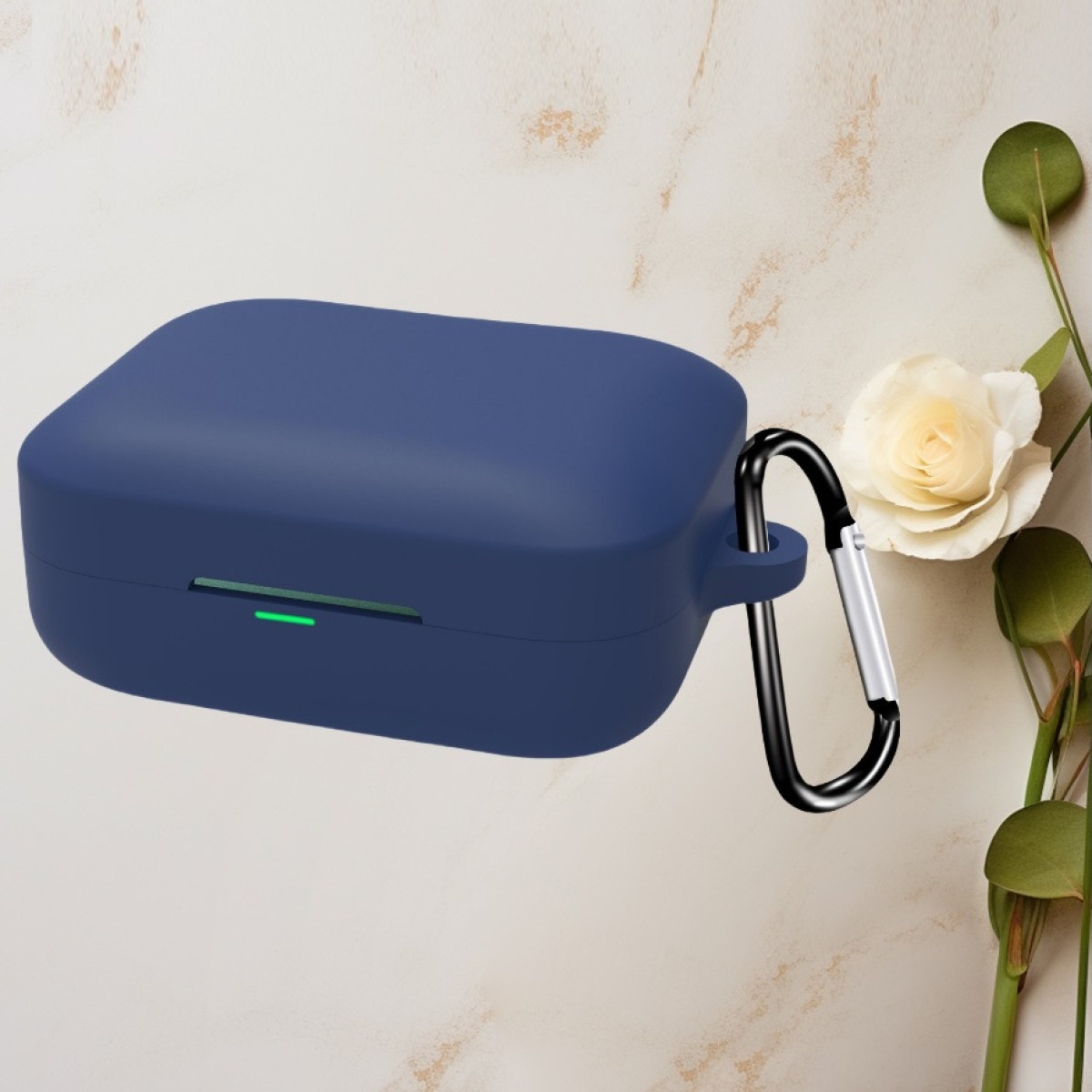 Custodia per auricolari blu navy con moschettone nero. Un fiore bianco e foglie verdi sullo sfondo.