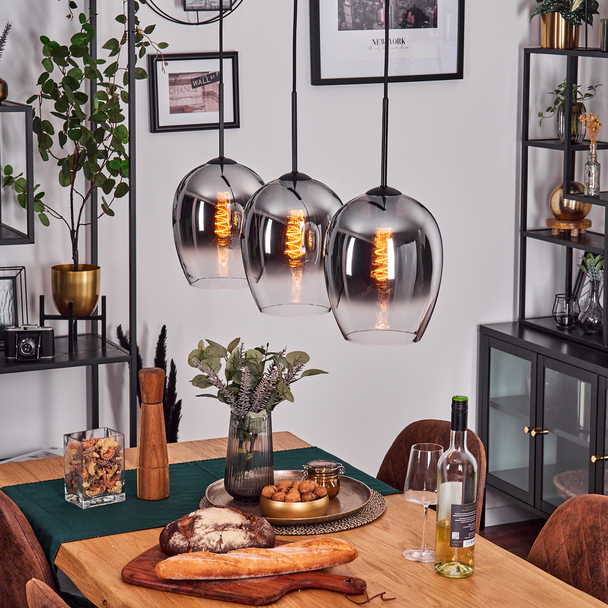 Esszimmer mit Hängelampen über einem Holztisch. Brot, Wein und andere Artikel auf dem Tisch.