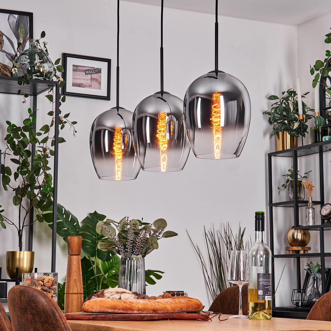 Drei Pendelleuchten hängen über einem Tisch mit Essen und Dekoration und schaffen eine einladende Atmosphäre.
