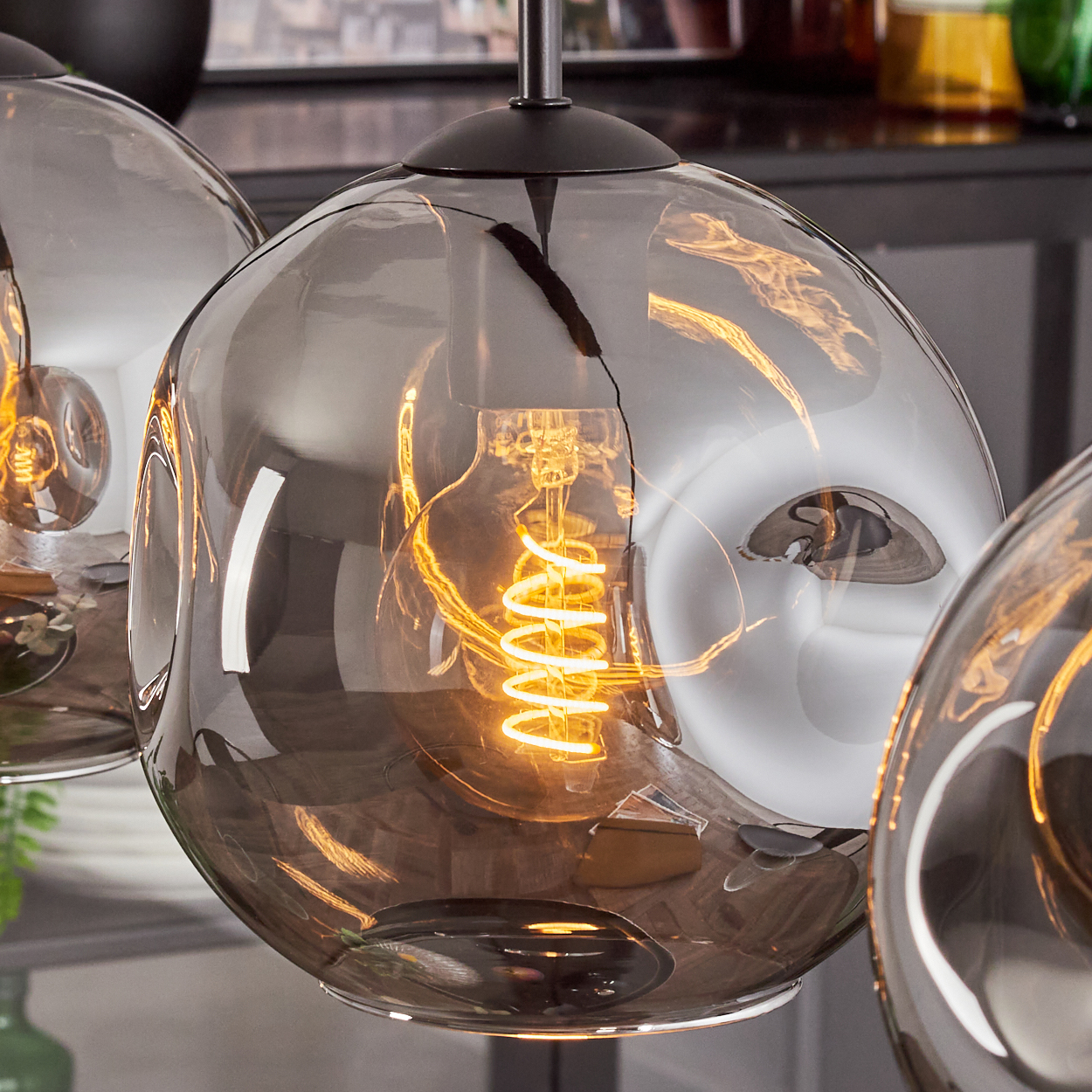Nahaufnahme einer Glaskugelleuchte mit einer Glühbirne. Das Glas hat ein verzerrtes, silberähnliches Aussehen.