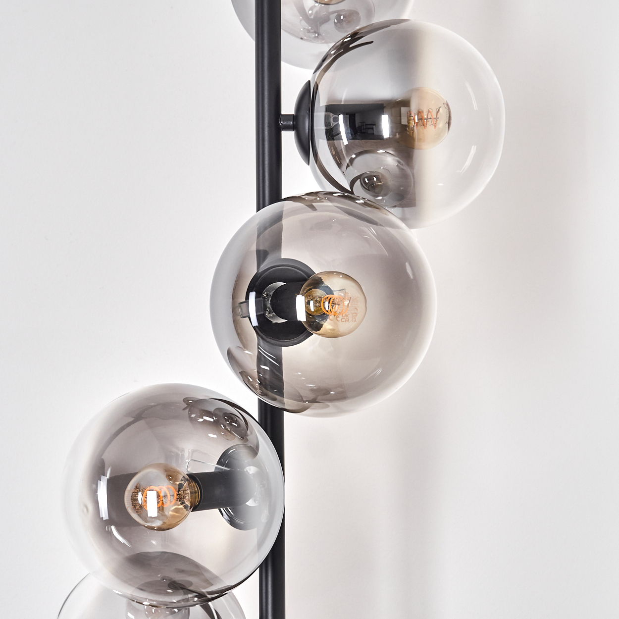 Nahaufnahme einer Stehlampe mit mehreren kugelförmigen Lichtern. Jedes Licht hat eine sichtbare Glühbirne.