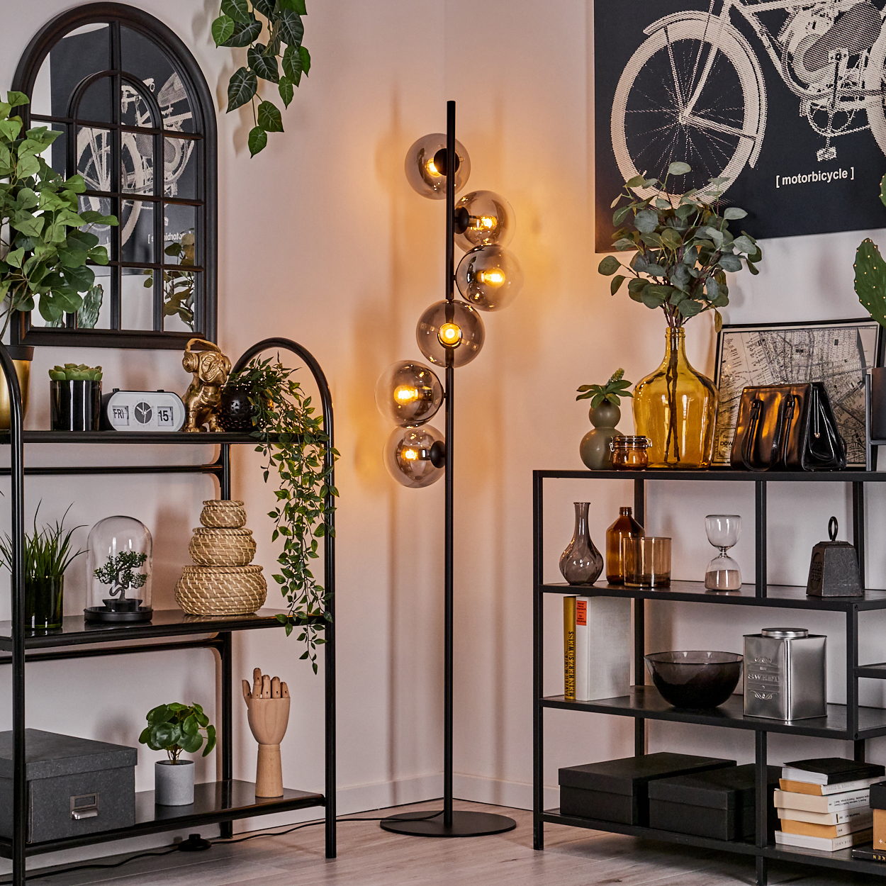 Ein Raum mit einer Stehlampe mit Glasschirm. Es gibt Regale und Dekoration.