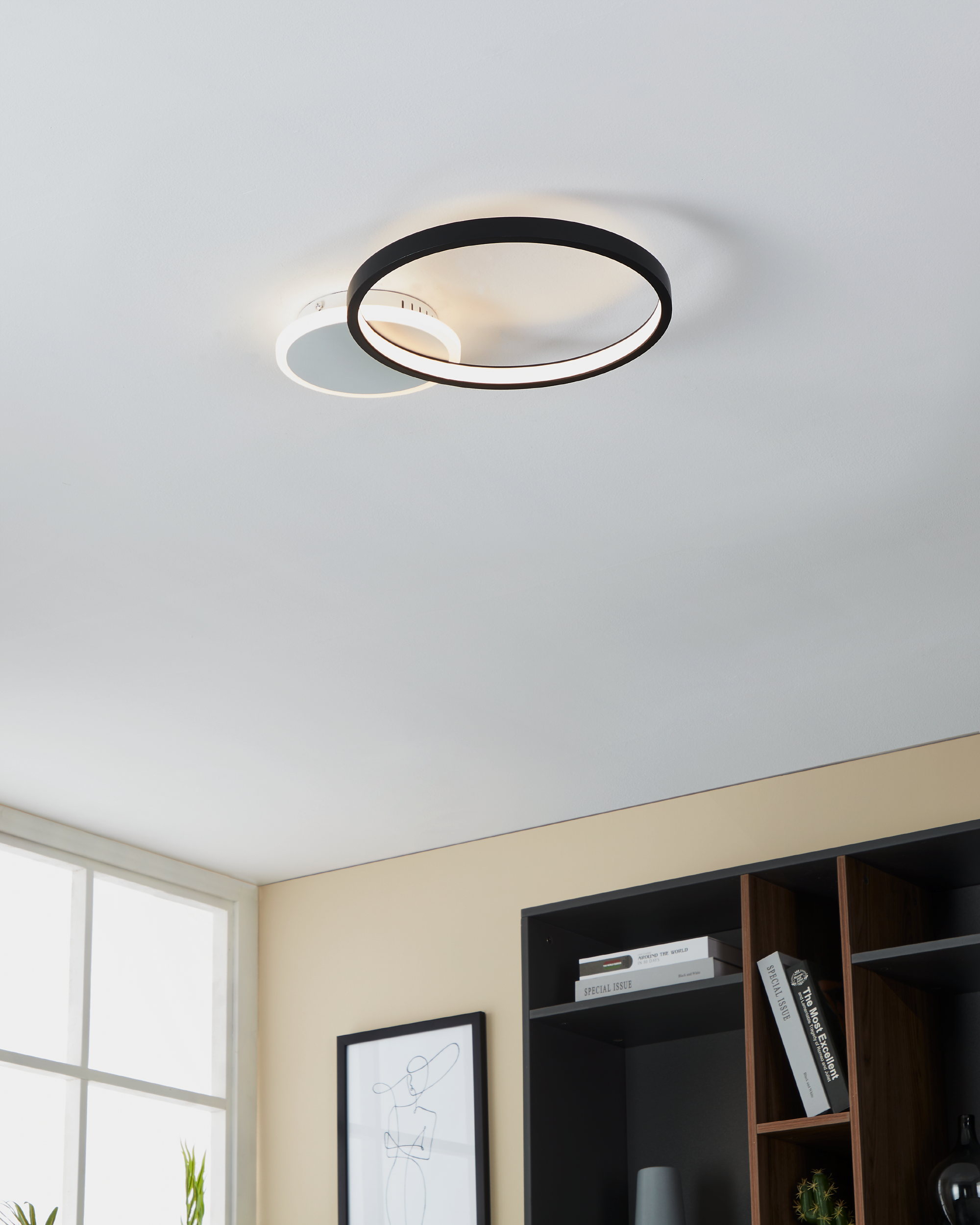 Eine moderne Deckenlampe mit zwei kreisförmigen Leuchten, eine weiße und eine schwarze, an einer weißen Decke.
