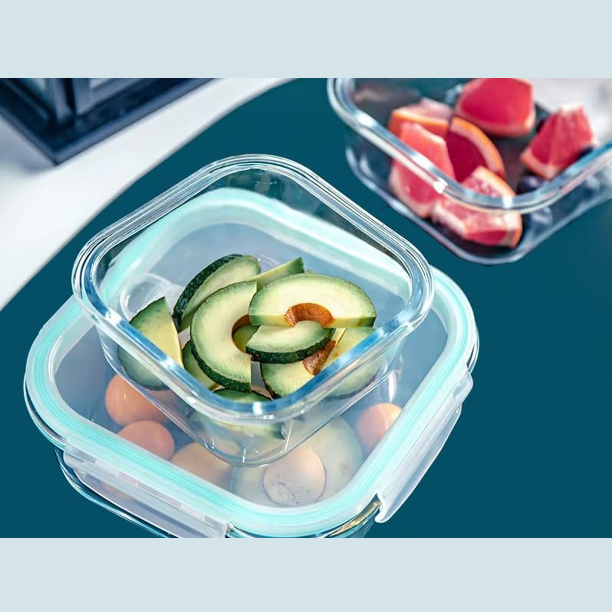 Recipientes de vidrio con rodajas de aguacate y toronja. Fondo azul.