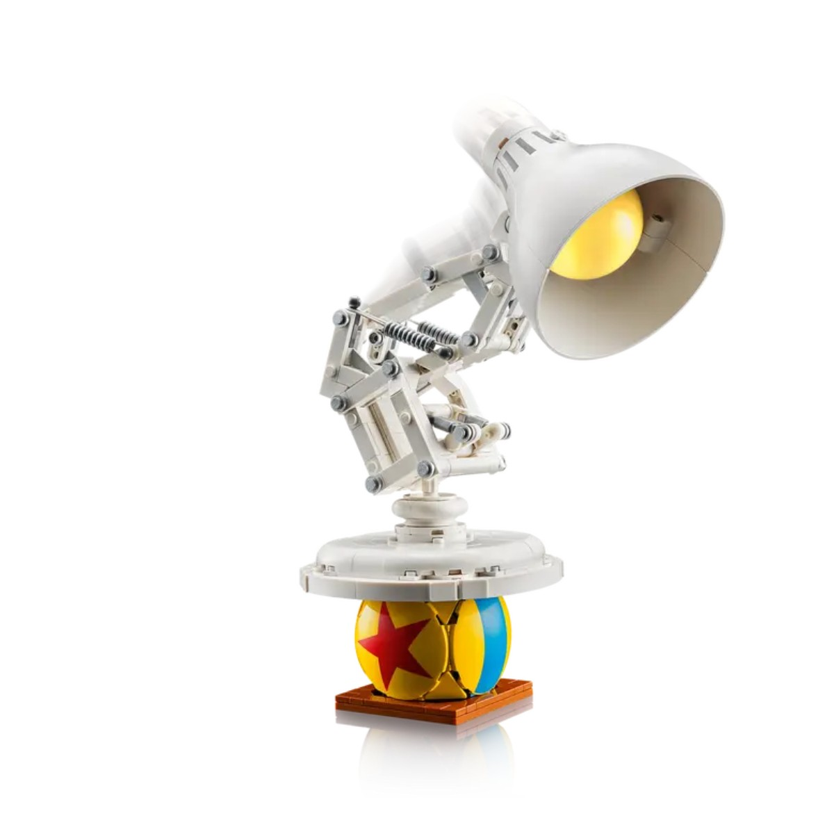 Lampa biurkowa z piłką i pudełkiem obok. Lampa jest włączona.