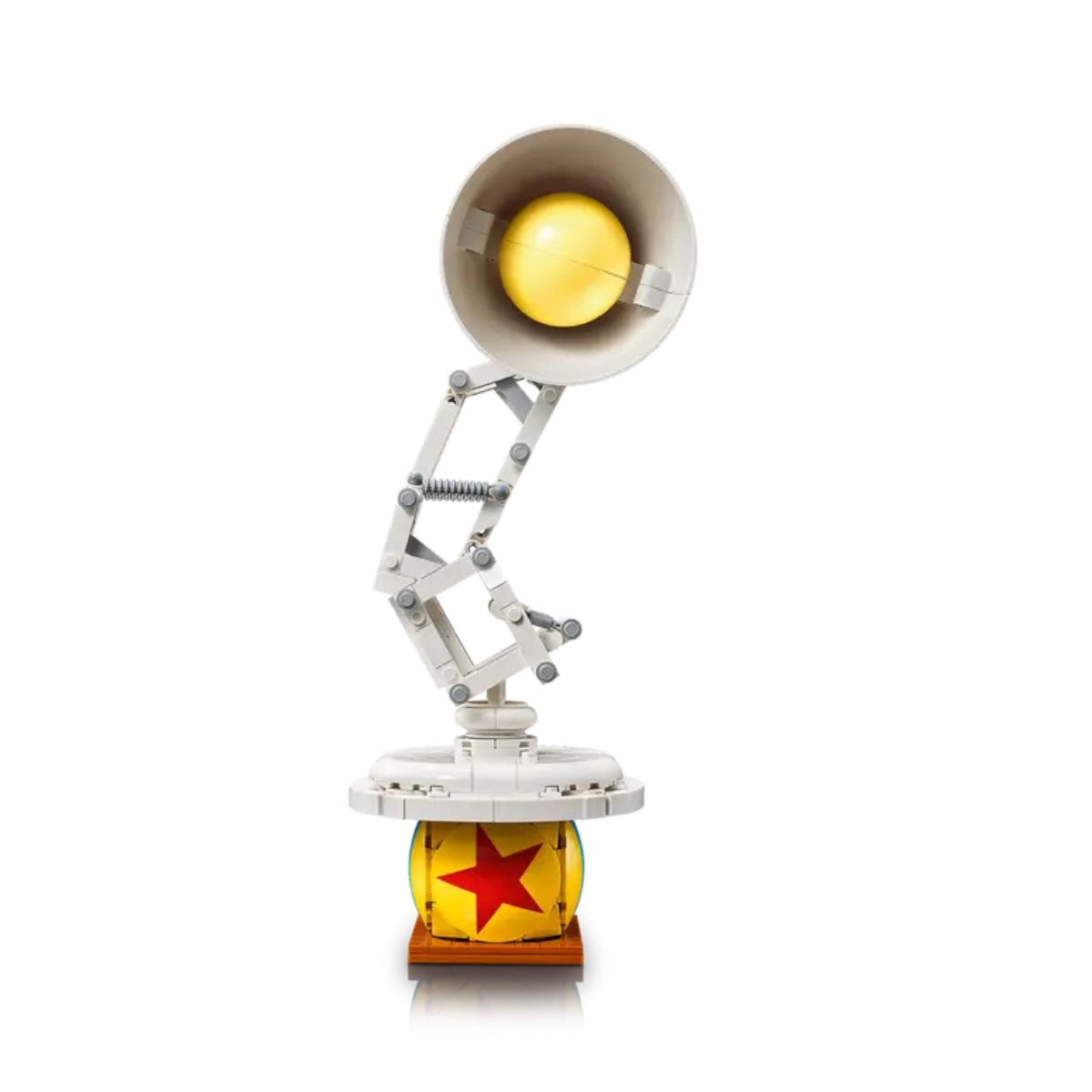 Zabawka Lego Pixar lampa. Żółta piłka pokryta gwiazdami na drewnianej podstawie z białą lampą.
