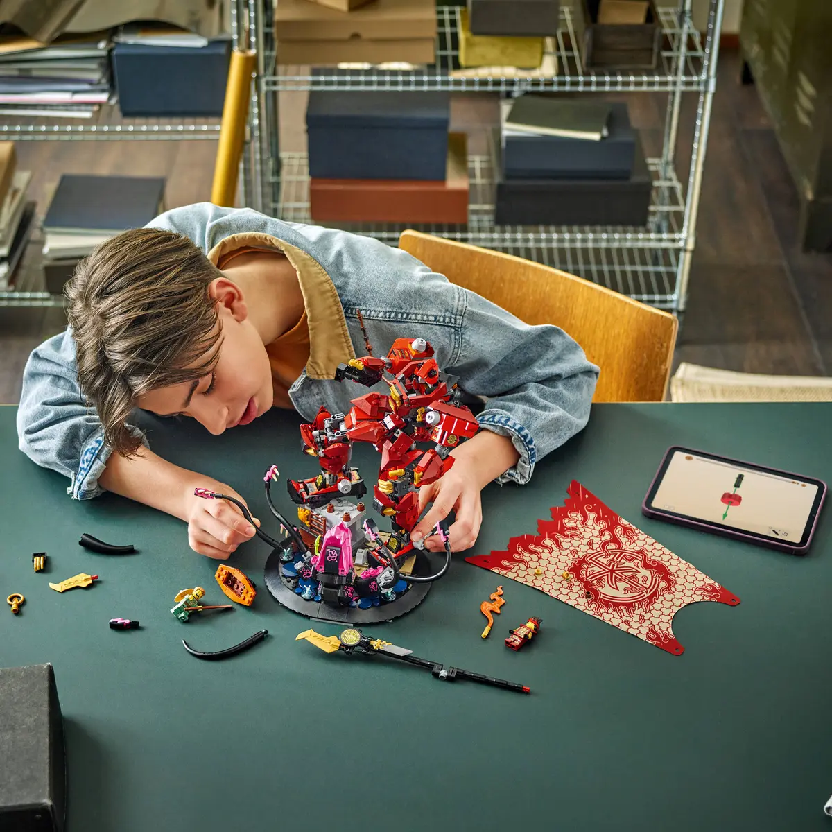 Chłopiec bawi się zestawem Lego. Skupia się na składaniu czerwonego robota Lego na ciemnozielonej powierzchni.