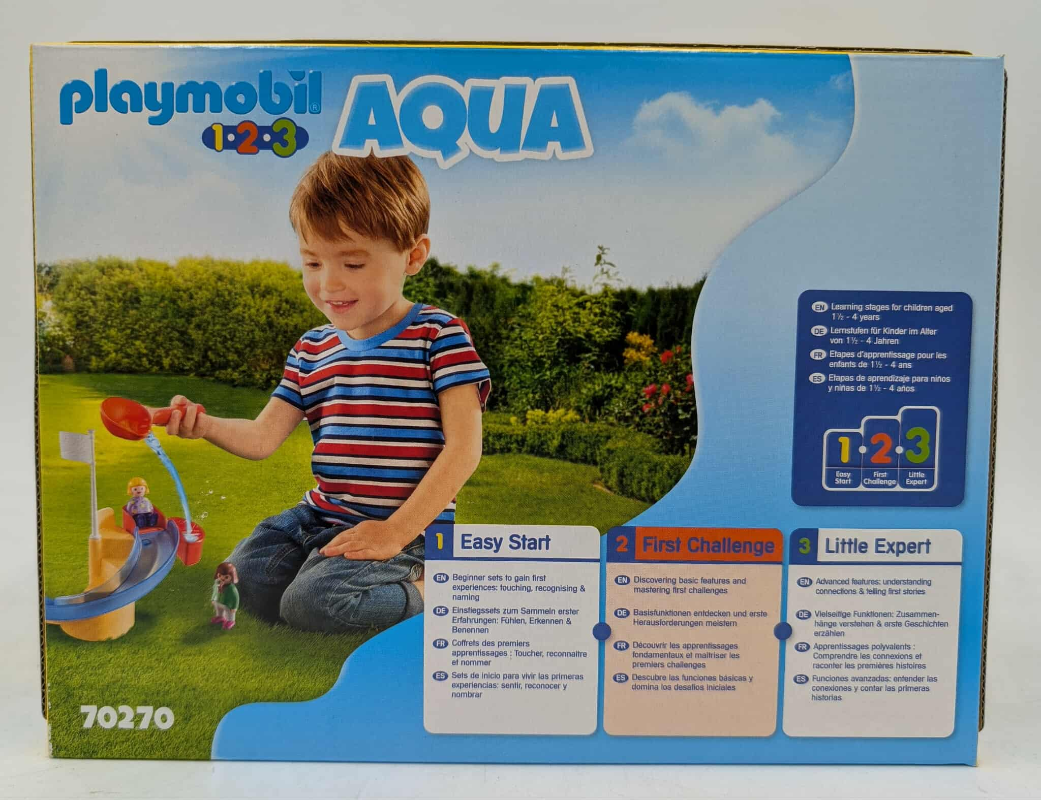 Playmobil 1-2-3 Aqua Box. Zeigt einen Jungen, der mit einem Wasserrutschen-Set mit einer Boje spielt. Der Text beschreibt die Produktmerkmale.