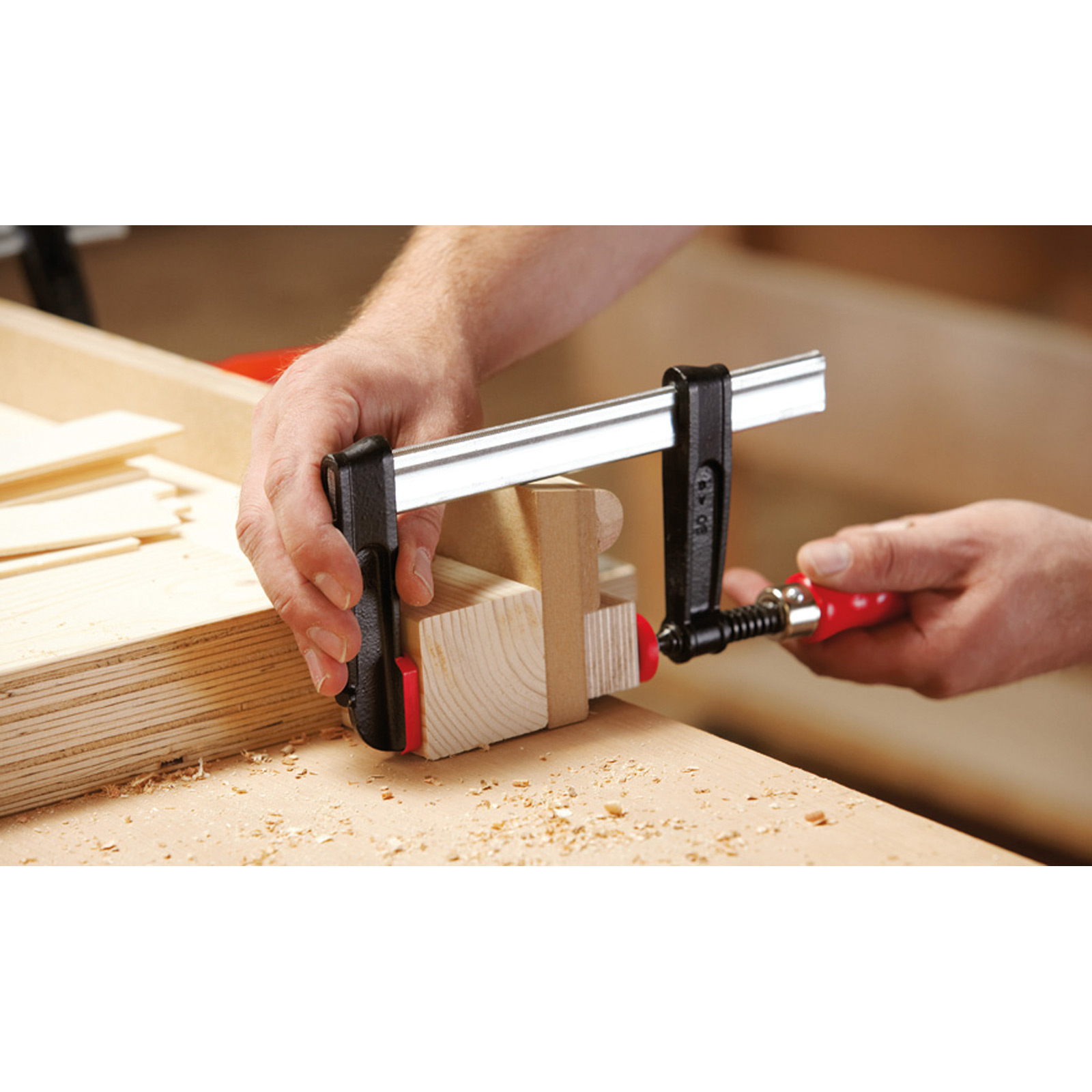 Eine Person, die eine Klemme verwendet, um Holzstücke zu sichern.