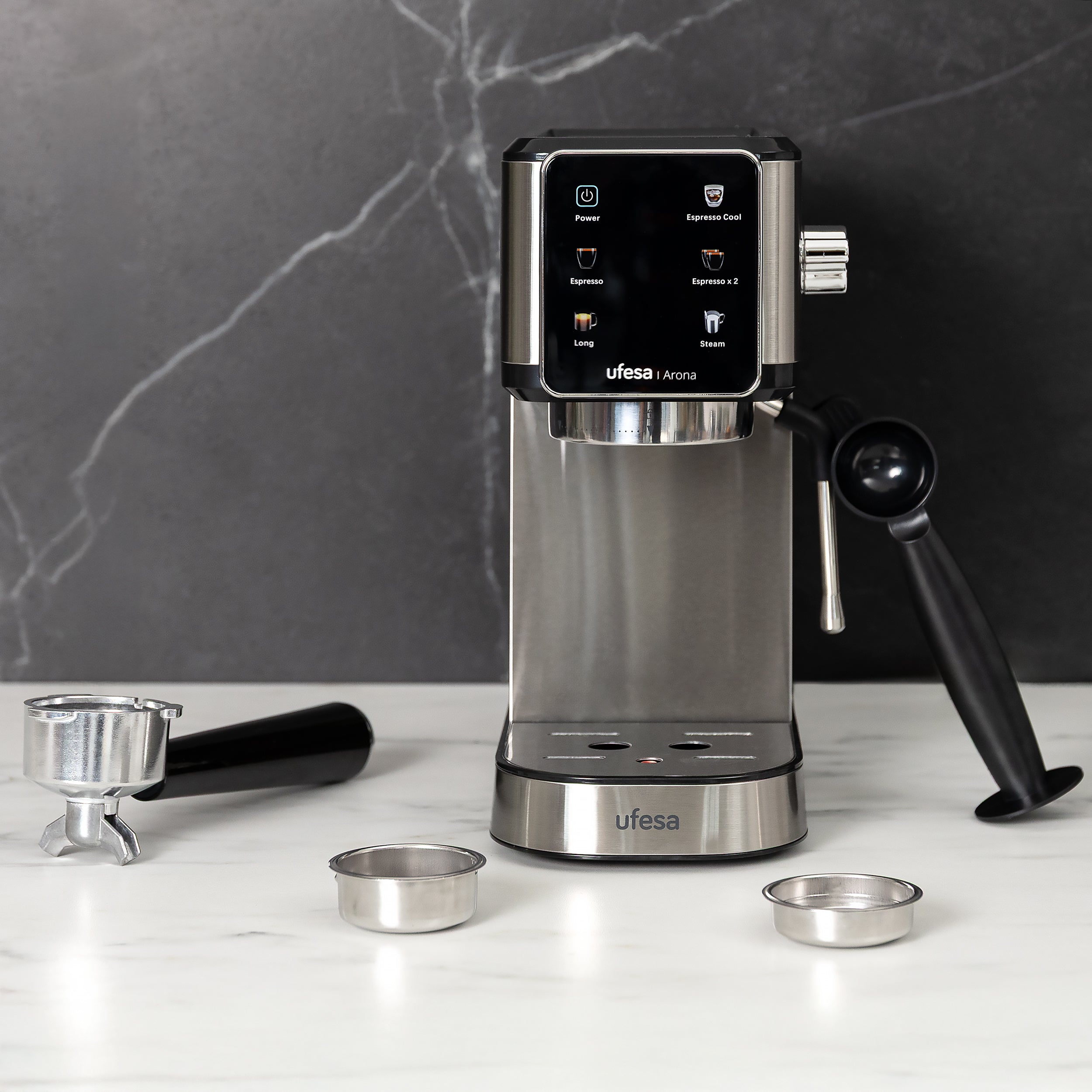 Máquina de espresso plateada y negra con accesorios sobre una encimera de mármol contra un fondo de mármol oscuro.