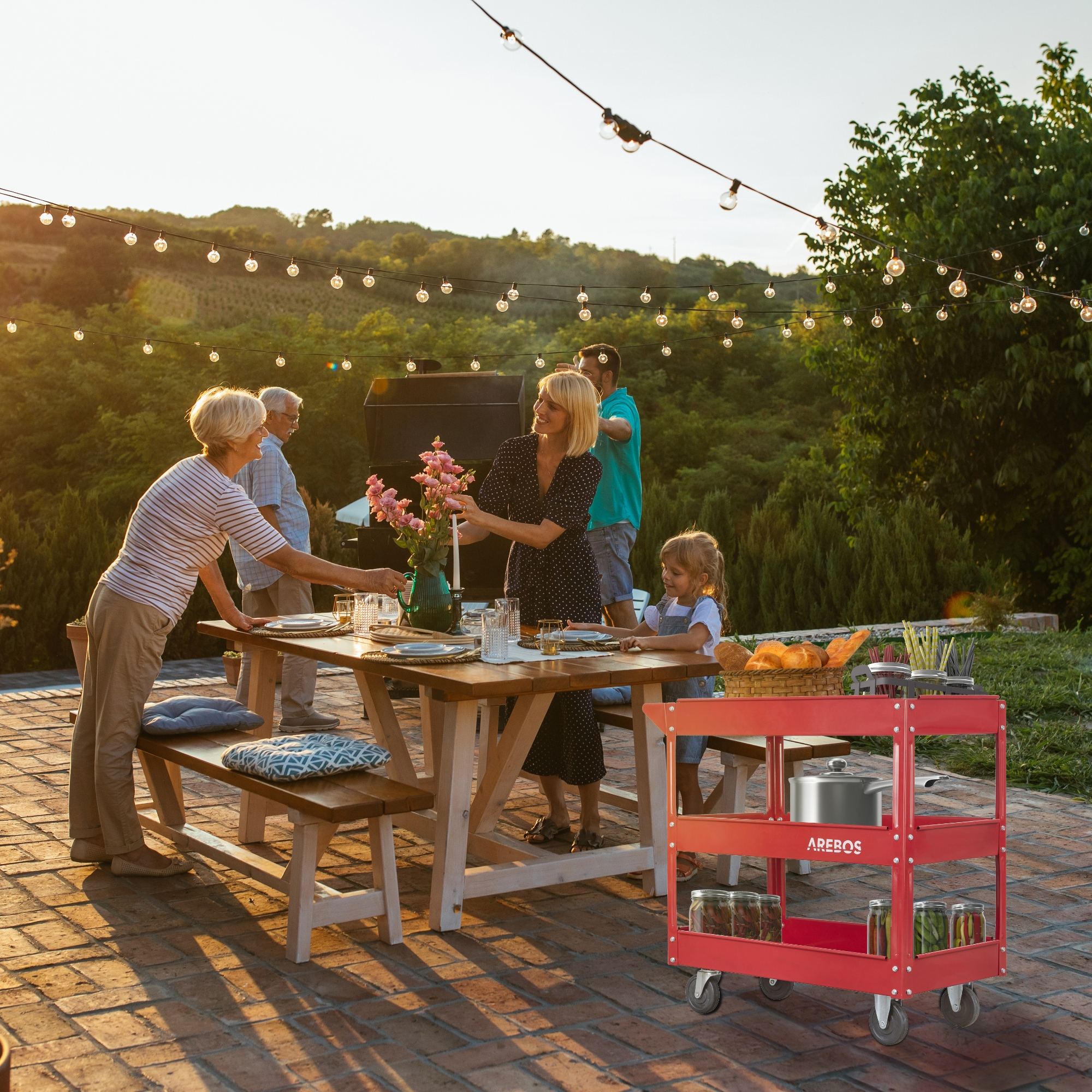 Familientreffen bei einer Gartenparty. Leute an einem Tisch, roter Wagen mit Essen, Lichterketten und Grill im Hintergrund.