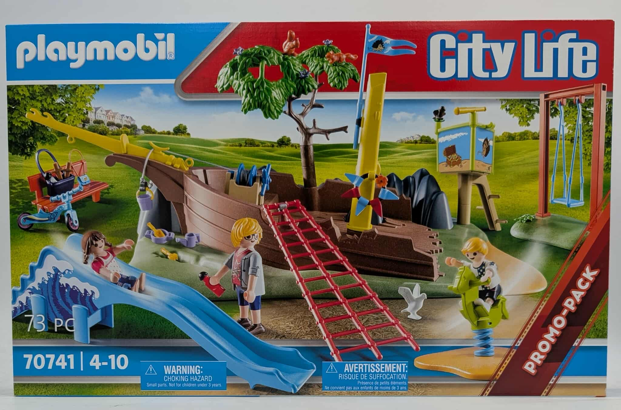 Playmobil City Life Box-Set mit einem Spielplatz mit Rutsche, Schiff und Figuren. Grünes Gras und blauer Himmel.