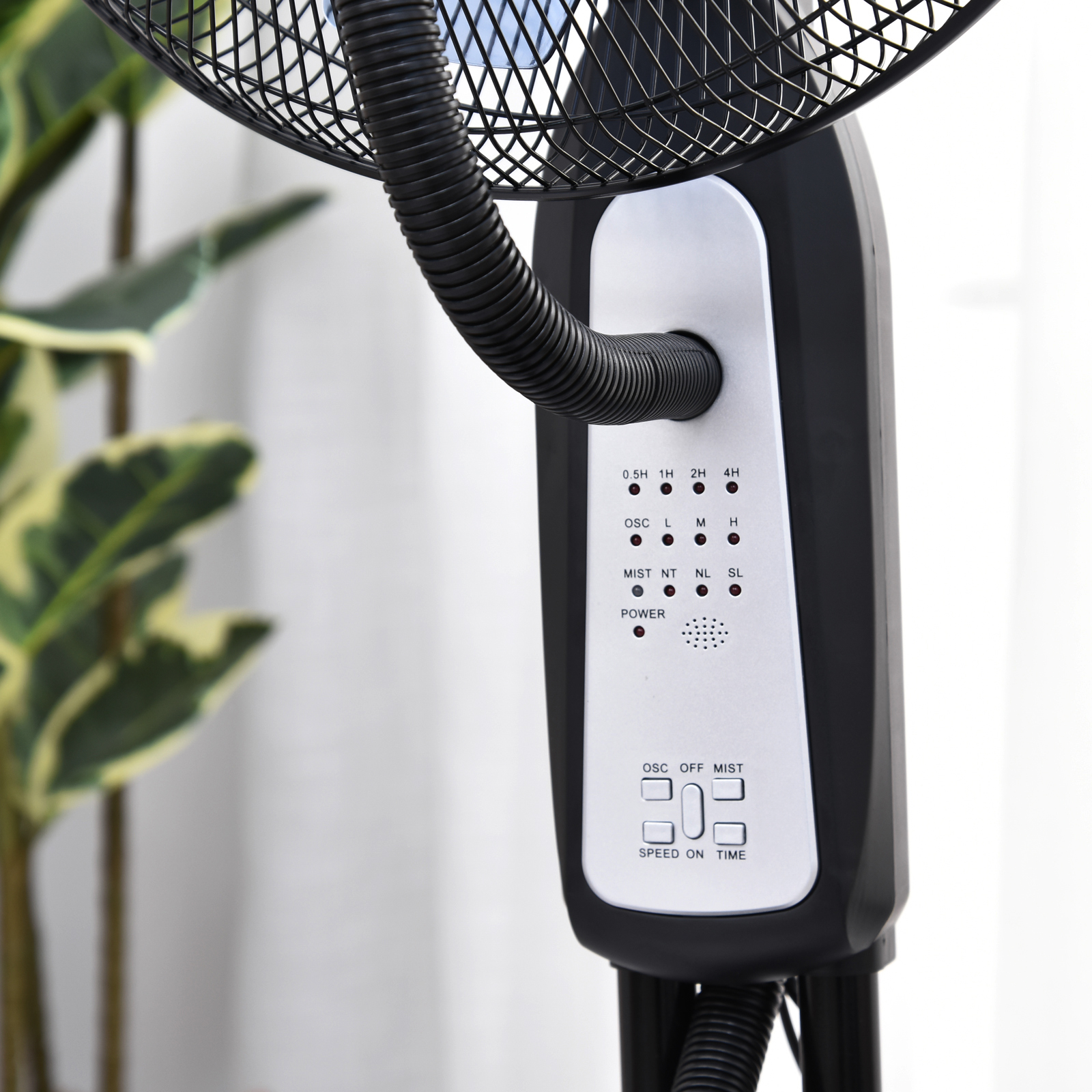 Primo piano del pannello di controllo di un ventilatore nebulizzatore nero davanti a una pianta.