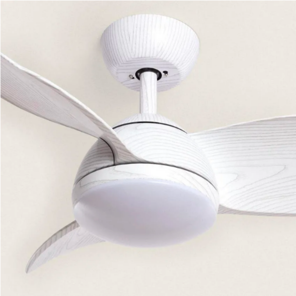 Un ventilatore da soffitto con tre pale bianche effetto legno e un apparecchio a globo bianco. Sfondo beige.