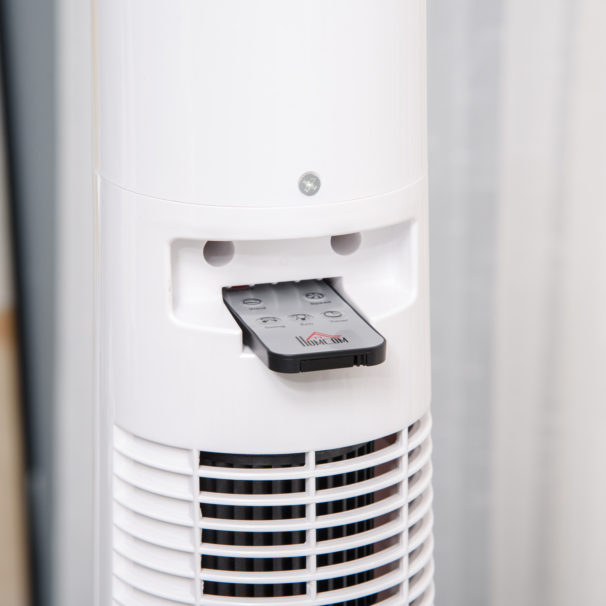 Un primo piano mostra un ventilatore a torre con un telecomando inserito, evidenziando il pannello di controllo.