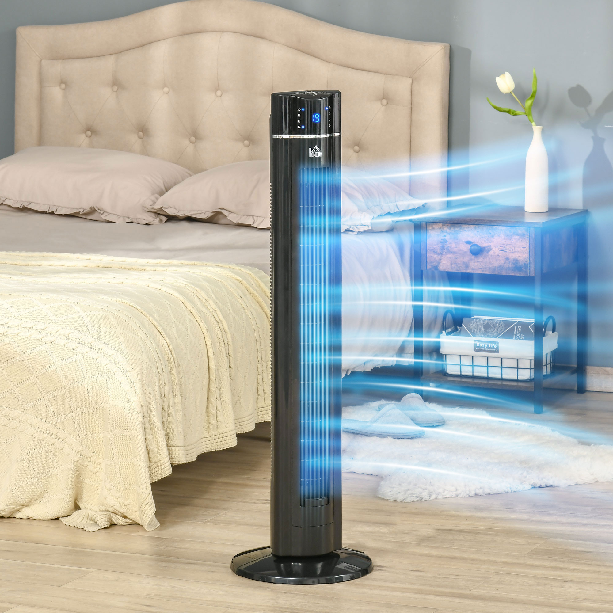 Il ventilatore a torre nero soffia aria fresca nella camera da letto. Letto, comodino e vaso con fiore nelle vicinanze.