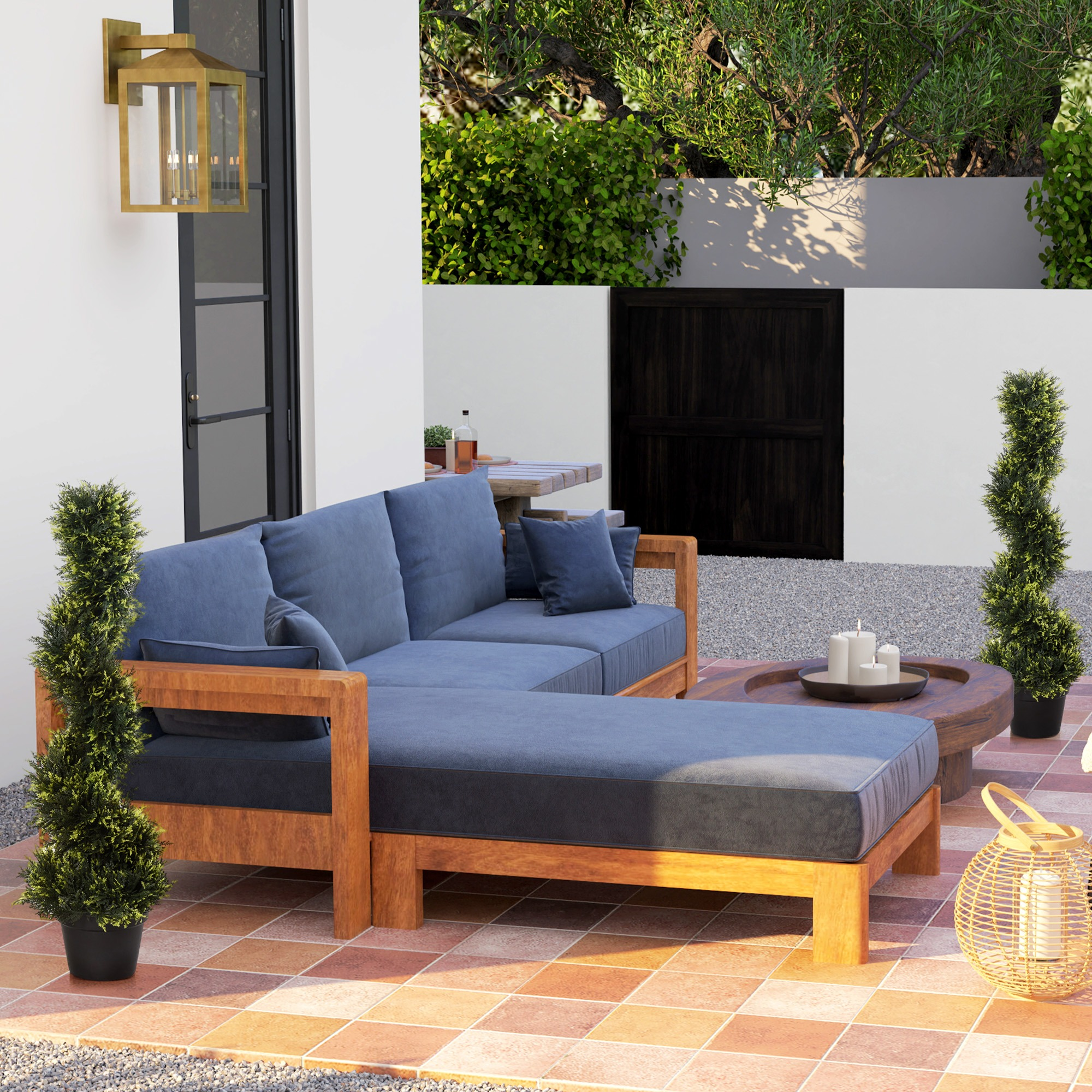 Außenszene mit blauem Sofa, Buchsbäumen und einer Laterne. Weiße Wand und Fliesenboden.