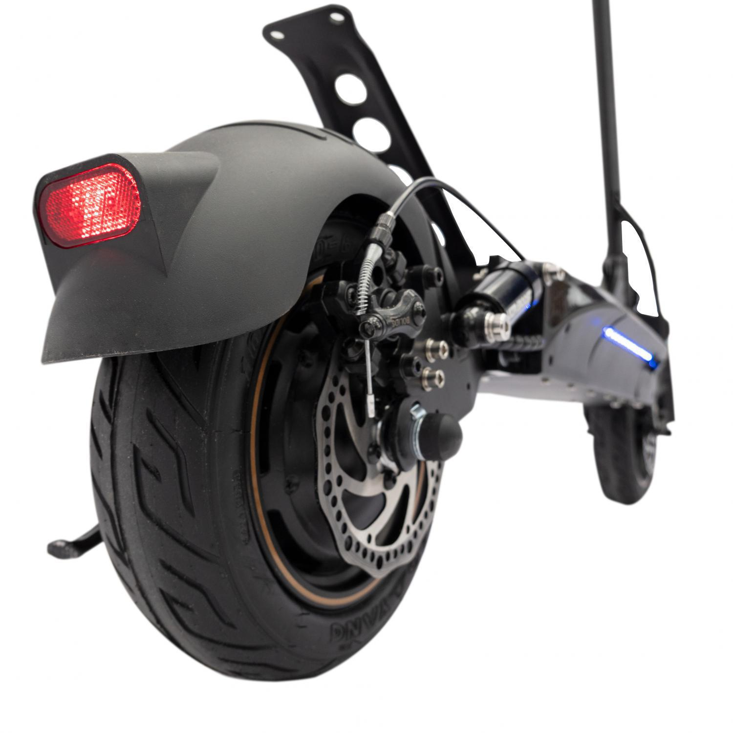 Primer plano de la rueda trasera de un scooter, mostrando el neumático, el disco de freno y los componentes de la suspensión.