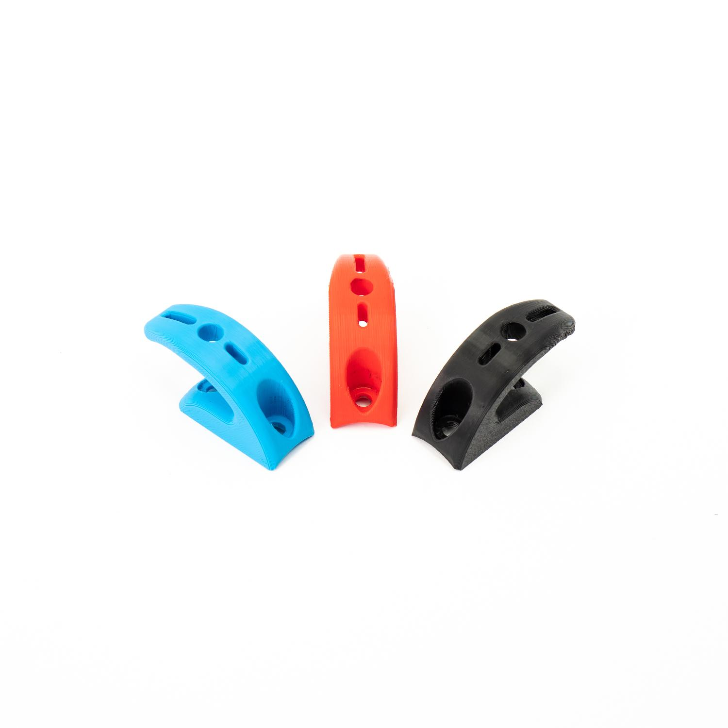 Tres clips de plástico en azul, rojo y negro, dispuestos sobre una superficie blanca.