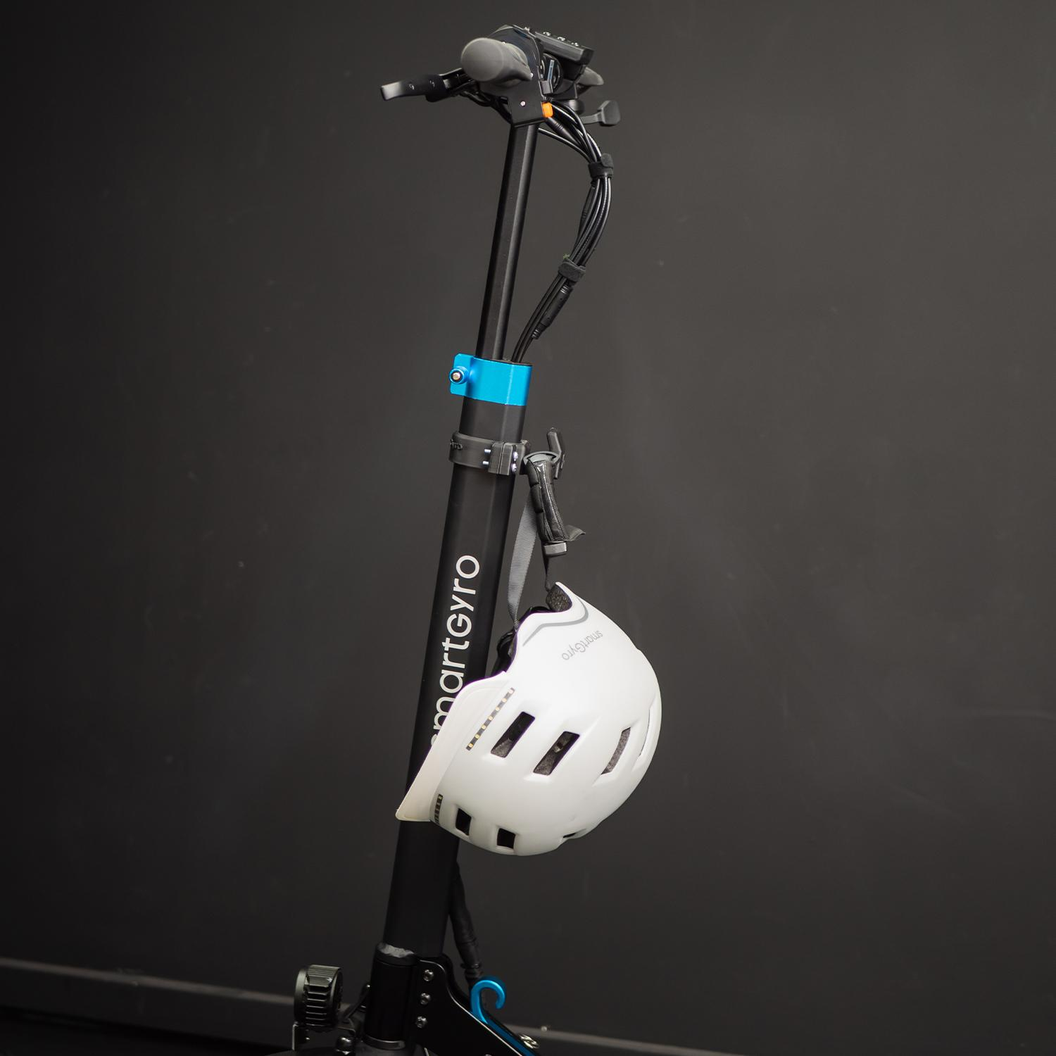 Un casco blanco colgado del manillar de un scooter negro sobre un fondo negro.