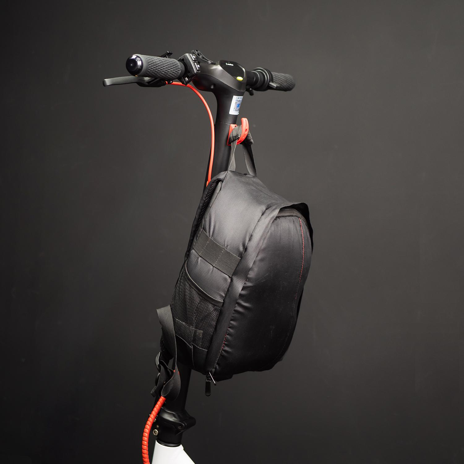 Una bolsa negra adjunta a un scooter. La bolsa tiene un detalle rojo y está colgando.