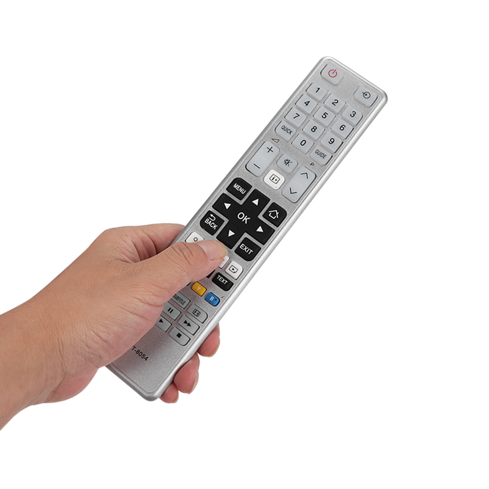 Die Hand einer Person hält eine silberne Fernbedienung mit vielen Knöpfen auf weißem Grund.