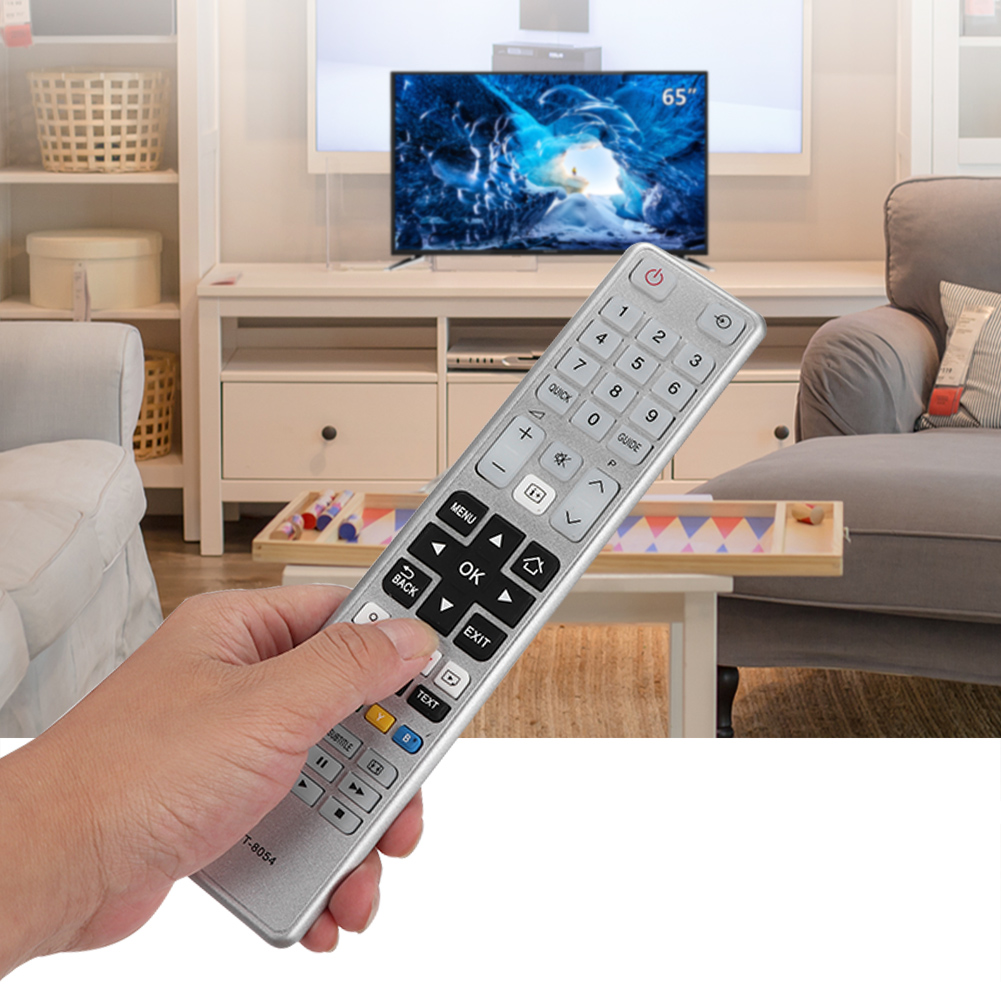 Eine Hand hält eine silberne TV-Fernbedienung vor einem Fernsehbildschirm. Die Fernbedienung zeigt auf den Bildschirm.