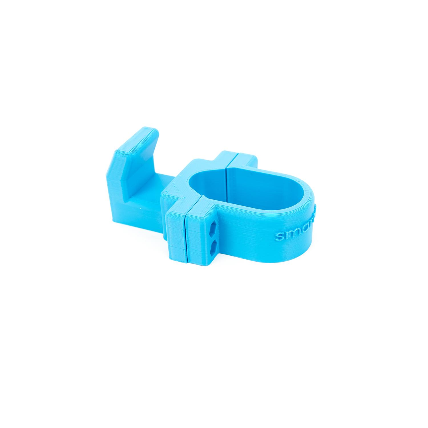 Un objeto azul claro impreso en 3D, un clip para cable, sobre un fondo blanco.