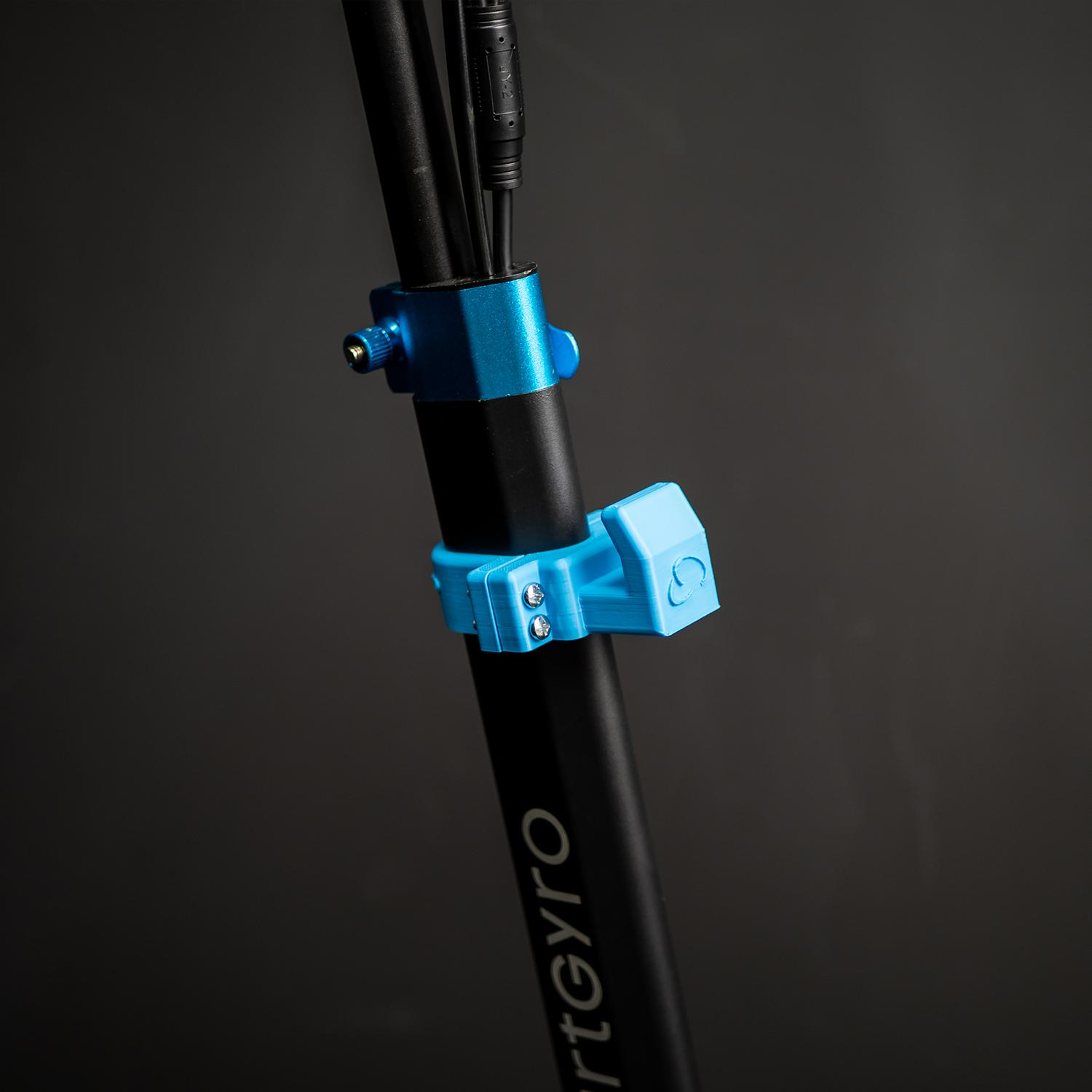 Primer plano del manillar de un scooter. Los soportes azules y los cables están sujetos a la columna de dirección.