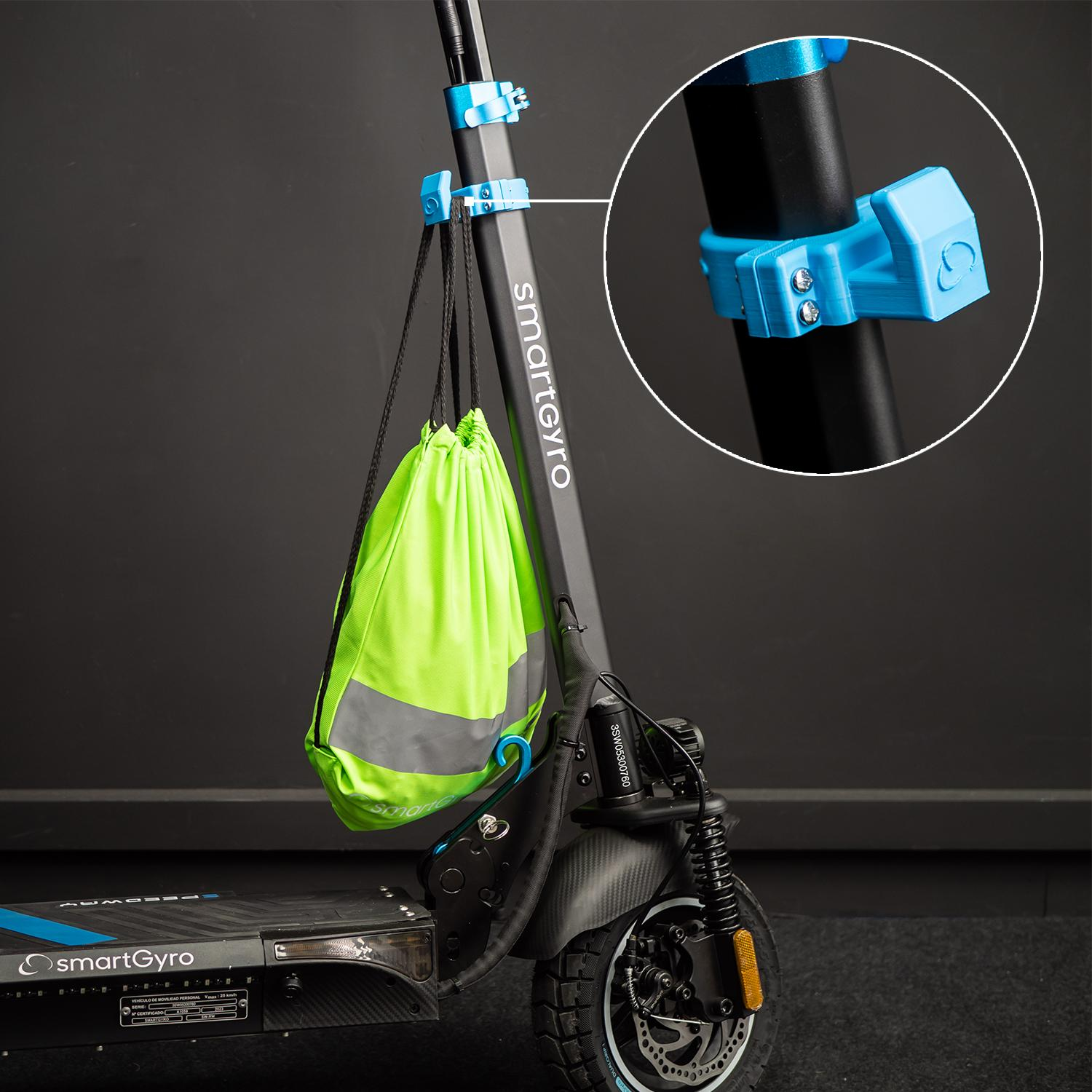 Un scooter tiene una bolsa verde colgando de él. El scooter es negro con detalles azules. La bolsa tiene rayas reflectantes.