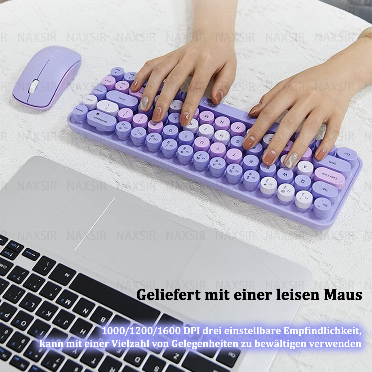 Hände tippen auf einer lila Tastatur mit passender Maus. Im Hintergrund befindet sich ein Laptop.