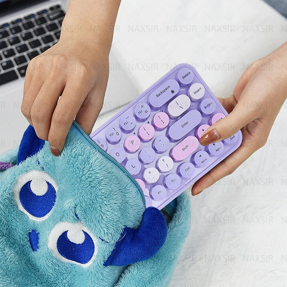 Eine Hand zieht eine lila Tastatur aus einer blauen, flauschigen Tasche.