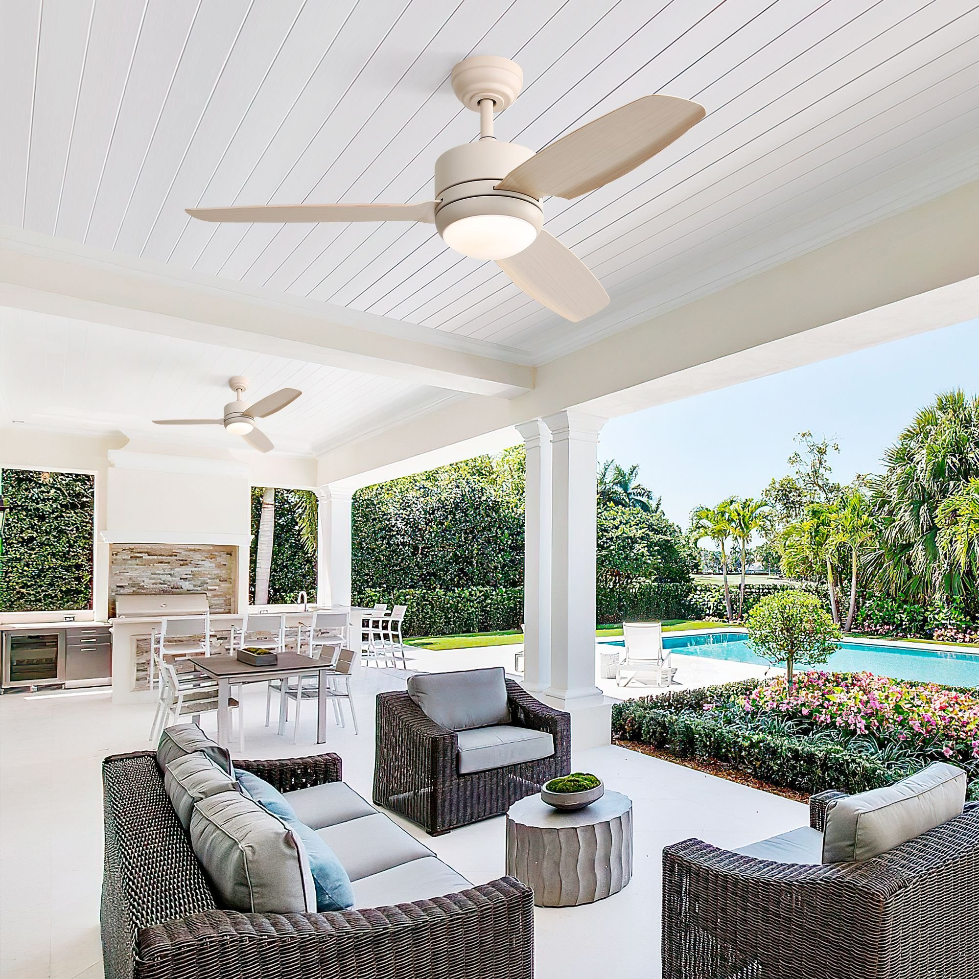 Eine Terrasse mit Deckenventilator. Zwei Ventilatoren an der Decke. Der Hintergrund zeigt einen Pool und üppiges Grün.