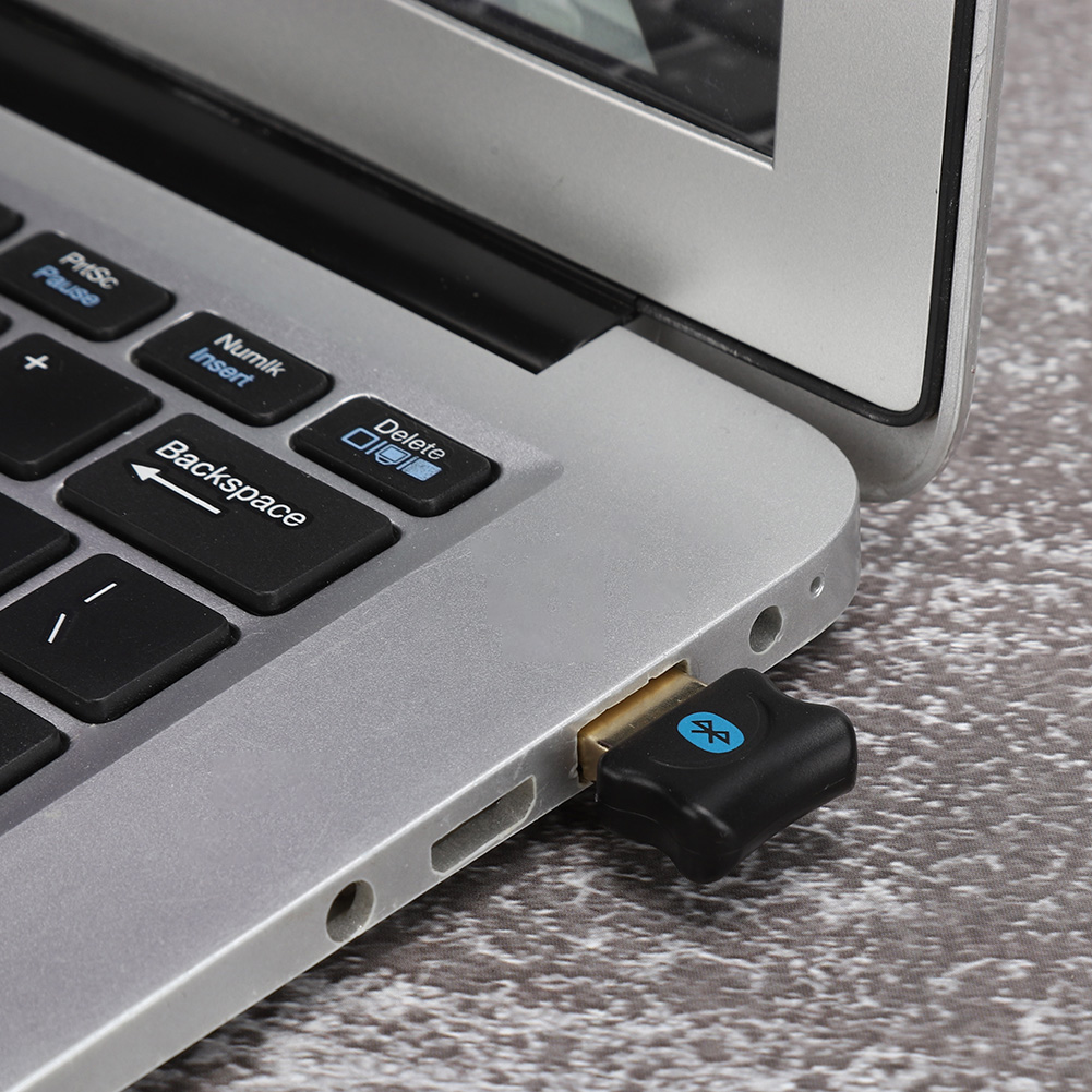 Laptop mit eingestecktem Bluetooth-Adapter. Der Adapter ist schwarz und blau.