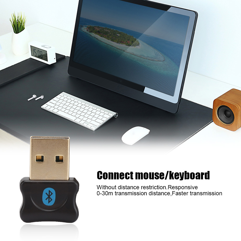 Ein schwarzer und goldener USB-Bluetooth-Adapter mit einem Computer und Zubehör im Hintergrund.