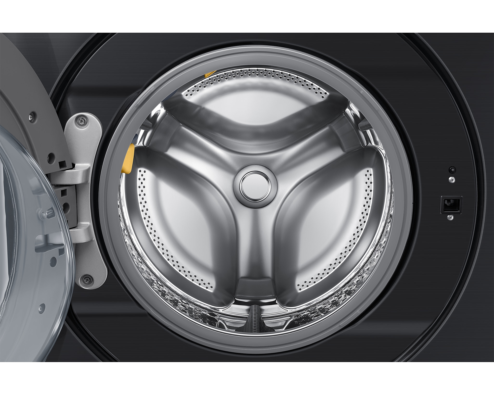 Zbliżenie na bęben pralki. Srebrny bęben z trzema wewnętrznymi łopatkami.