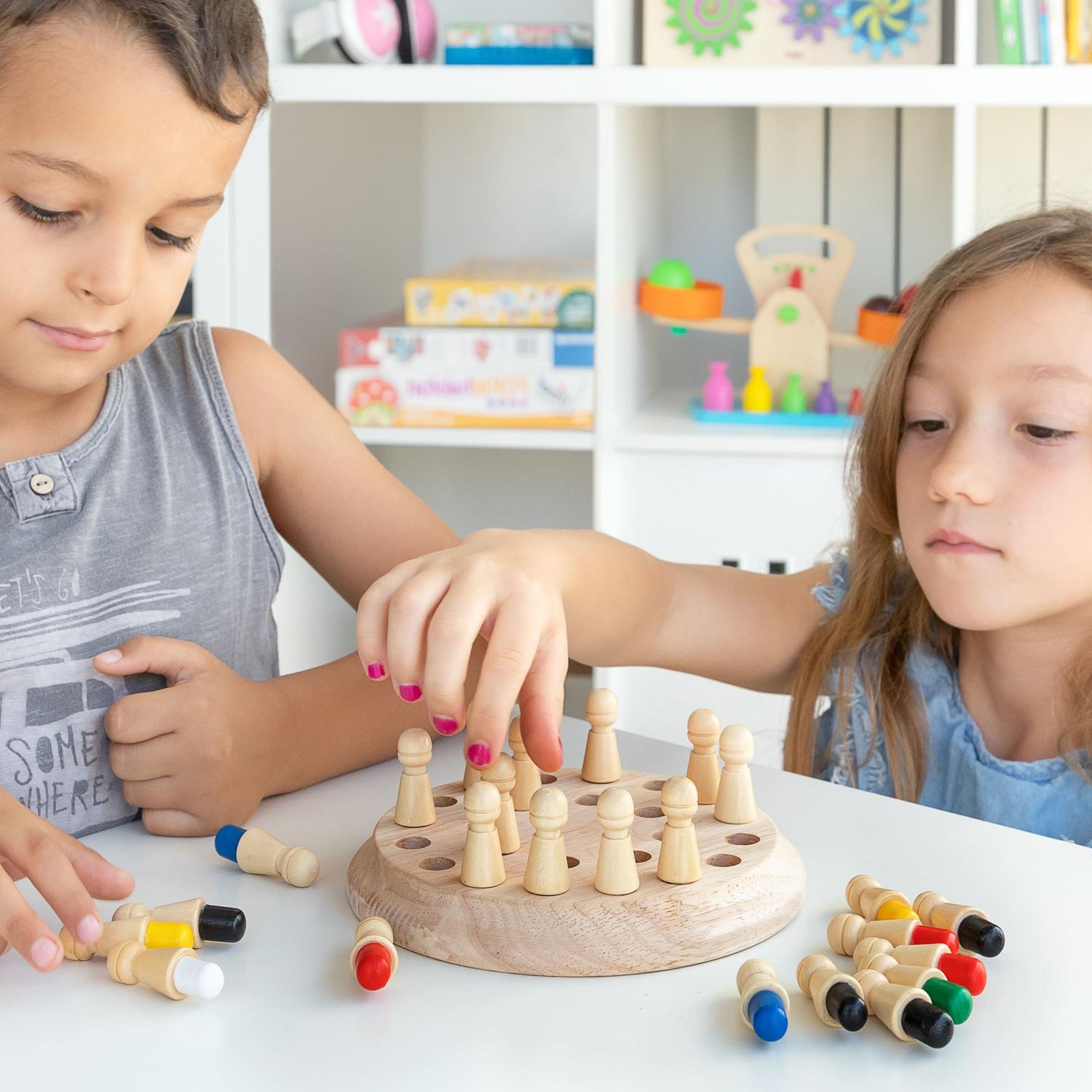 Due bambini giocano a un gioco da tavolo, con altri giocattoli sullo sfondo.