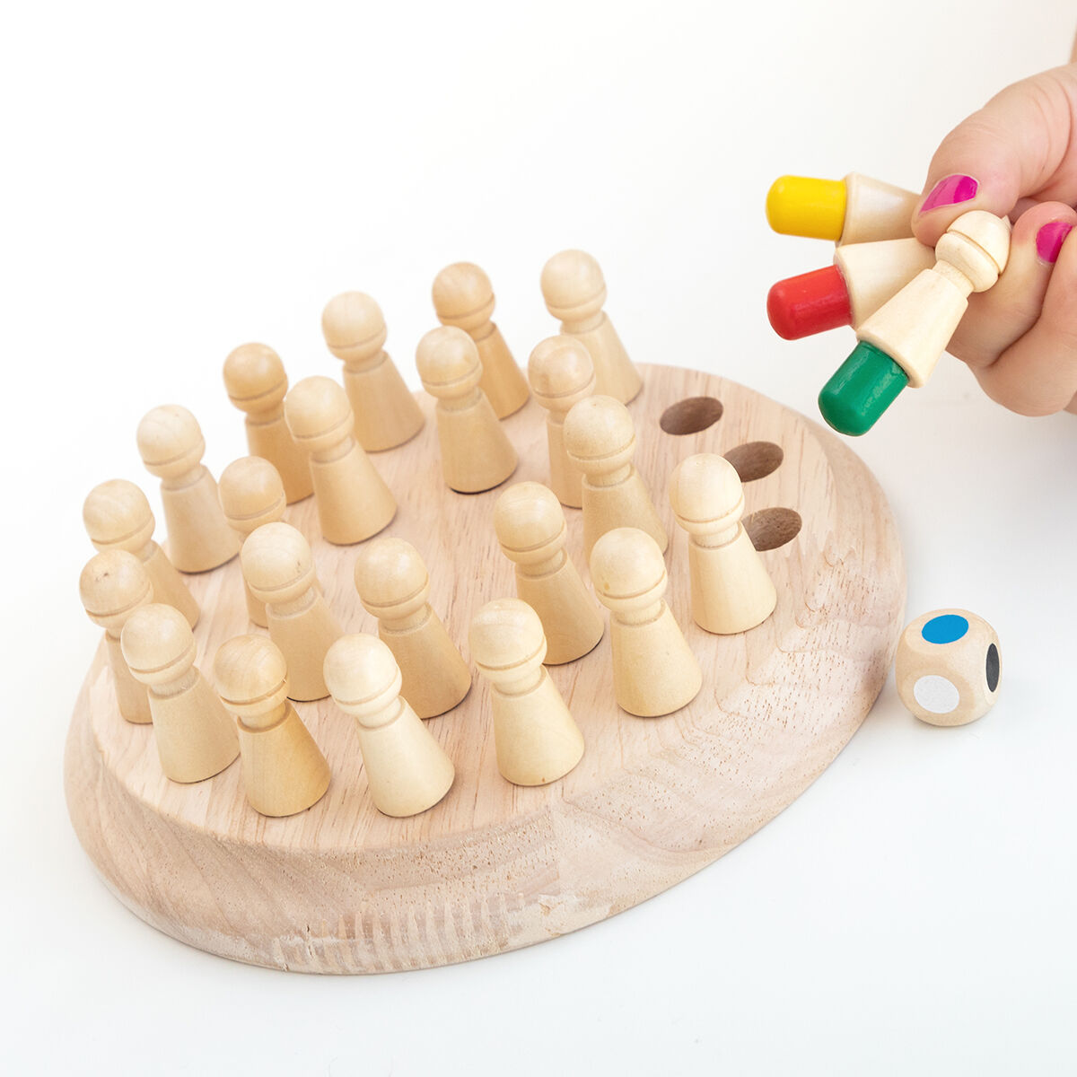 Mano che tiene pioli vicino a un gioco da tavolo e dadi su una superficie bianca.