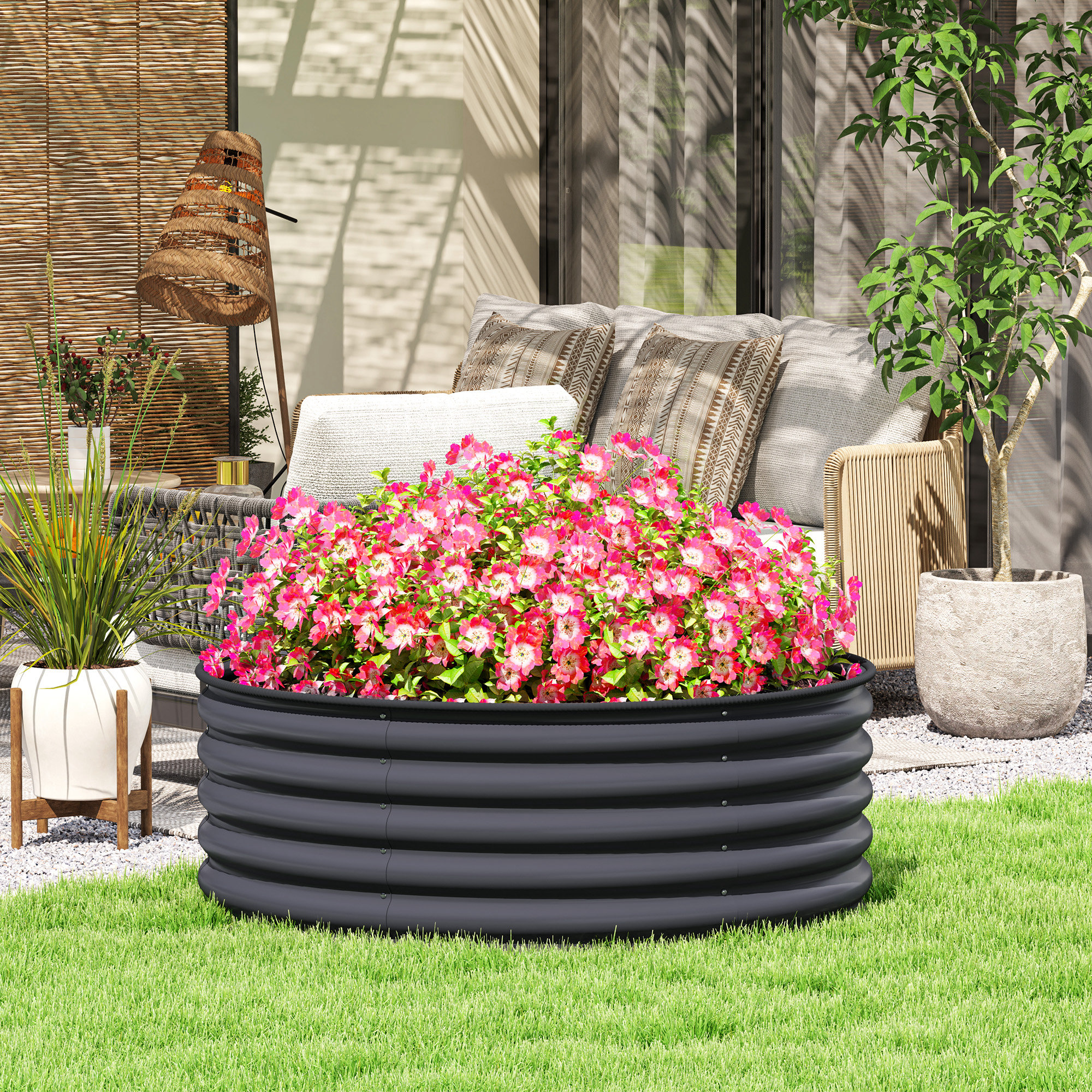 Ein rundes Hochbeet ist mit rosa Blumen gefüllt. Es steht auf grünem Gras in einer sonnigen Umgebung.
