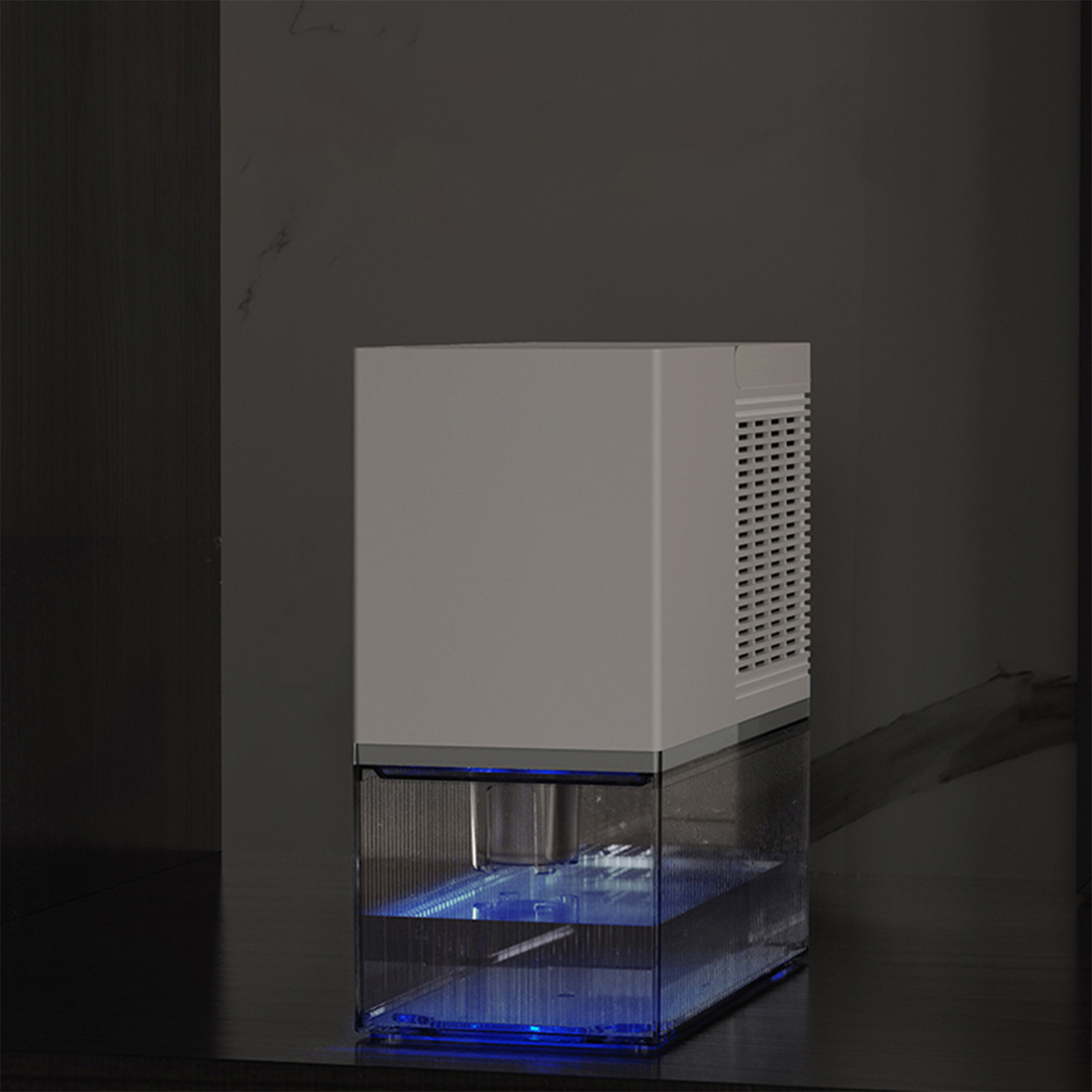 Ein weißer Luftentfeuchter mit transparentem Wassertank. Die Basis leuchtet blau, steht auf dunkler Oberfläche.