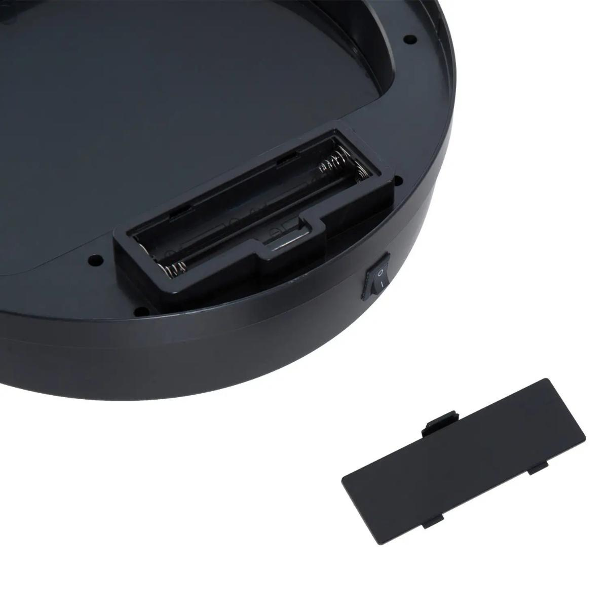 Die Unterseite eines schwarzen Geräts mit Batteriefach und Schalter wird gezeigt. Die Batterieabdeckung ist separat.