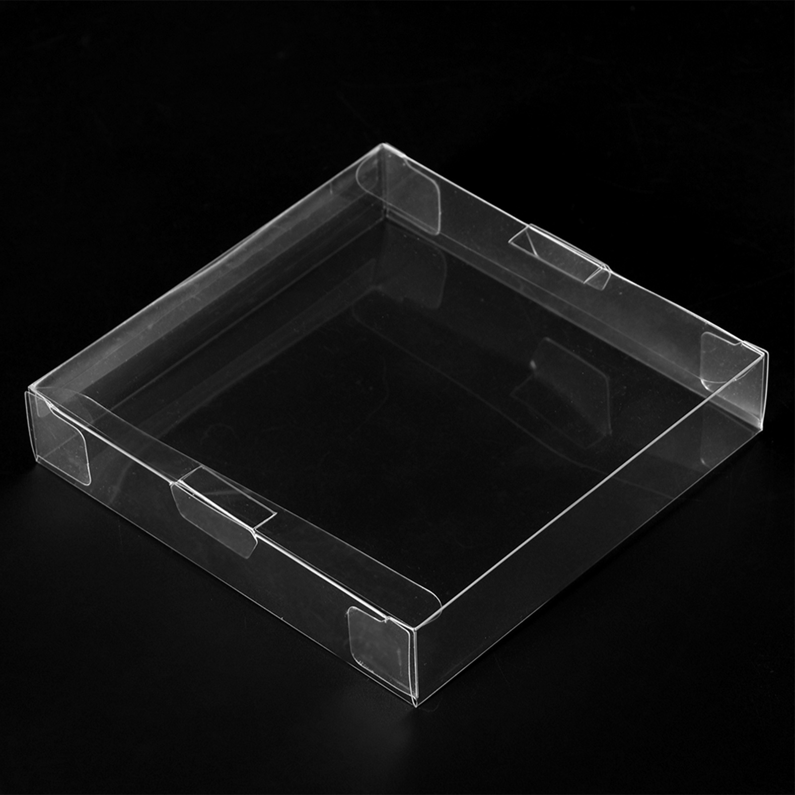 Eine transparente quadratische Box mit schwarzem Hintergrund. Die Box hat einen Deckel und ist leer.