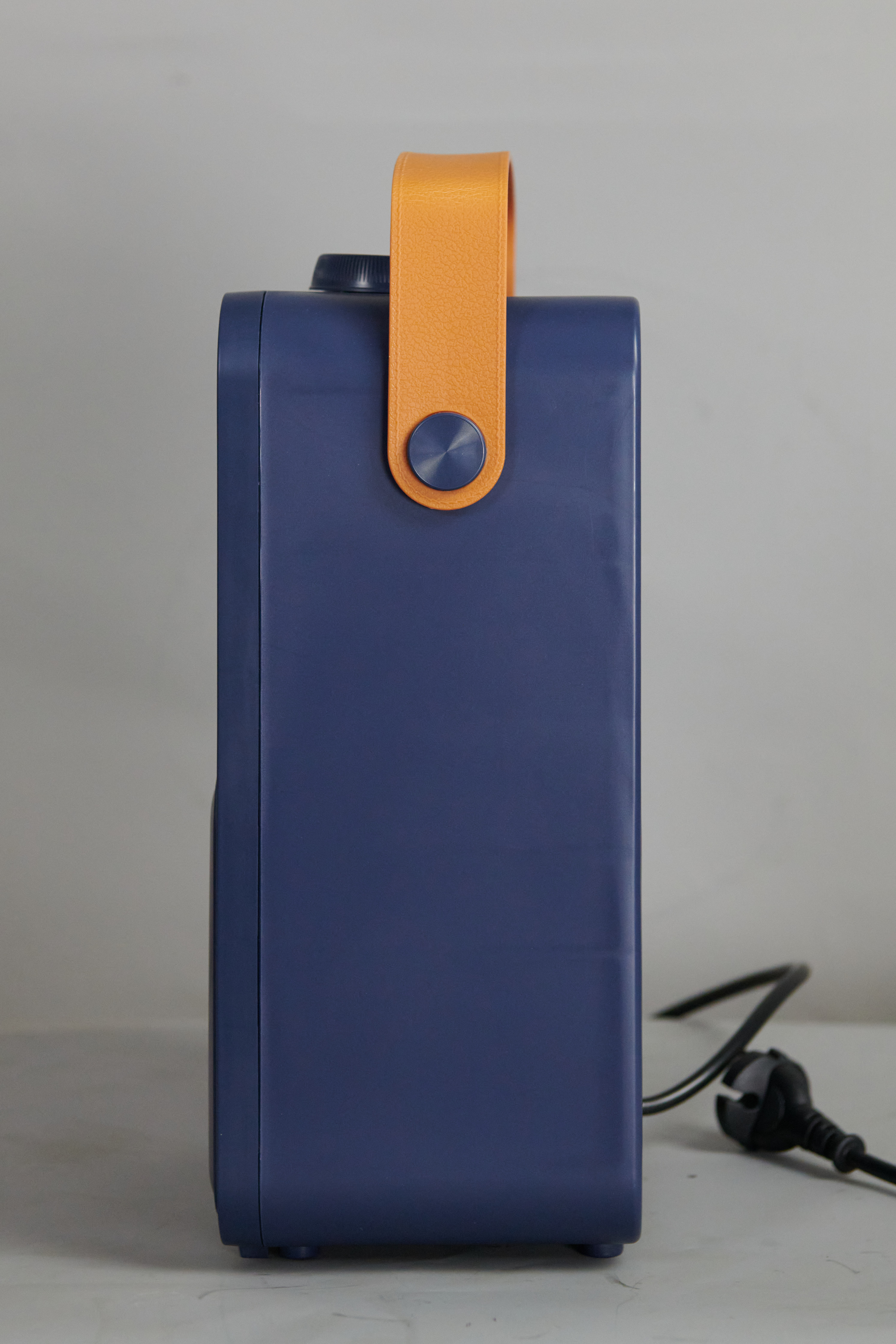 Seitenansicht einer blau-orangen Heizung. Sie hat einen orangefarbenen Griff und ein schwarzes Kabel.