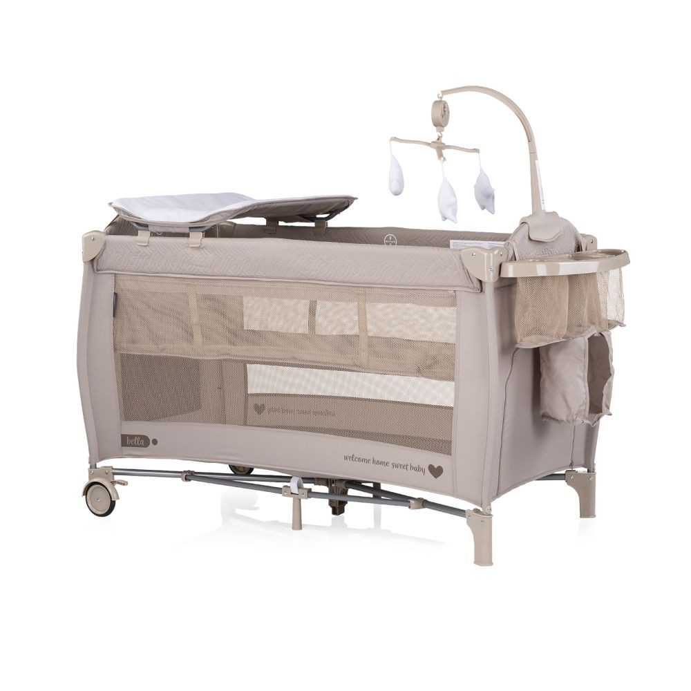 Beiges Babybett mit Mesh-Seiten, Wickelstation und Mobile. Es steht auf weißem Hintergrund.
