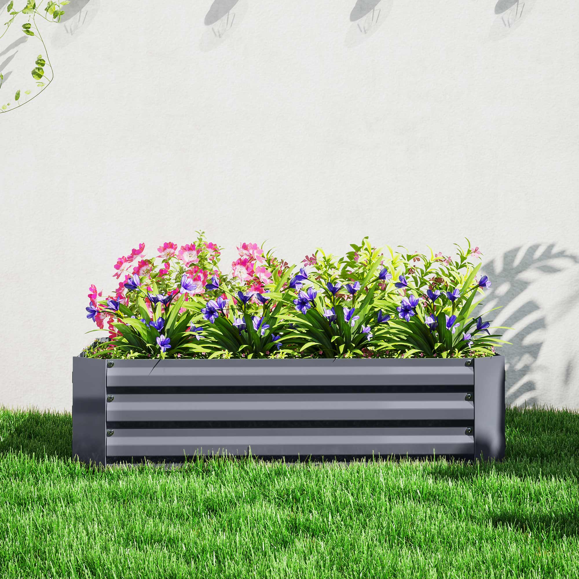Rechteckiges, erhöhtes Hochbeet mit Blumen gefüllt. Grünes Gras umgibt das Beet.