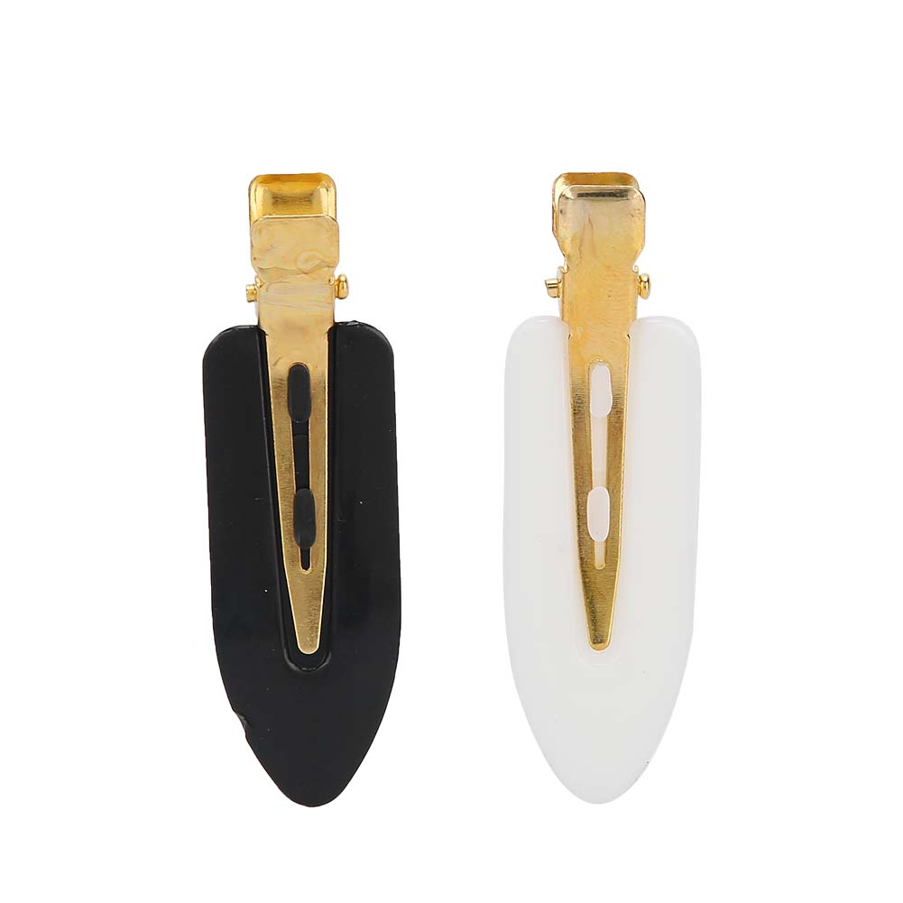 Zwei schwarz-weiße Haarspangen mit Goldmetall. Die Spangen sind wie ein abgeflachter Tropfen geformt.
