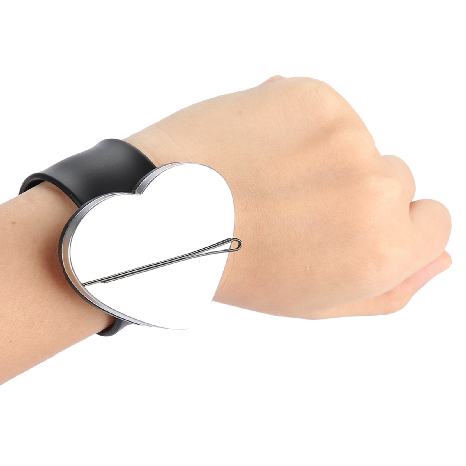 Hand mit schwarzem Armband, herzförmiger Silberplatte und schwarzer Haarnadel.